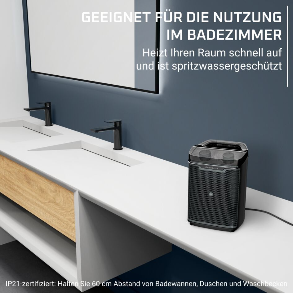 Un termoventilatore nero su un mobile da bagno bianco accanto ai lavandini.