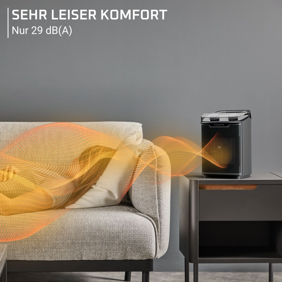 Un termoventilatore nero su un tavolino accanto a un divano, con testo sopra sulle prestazioni.