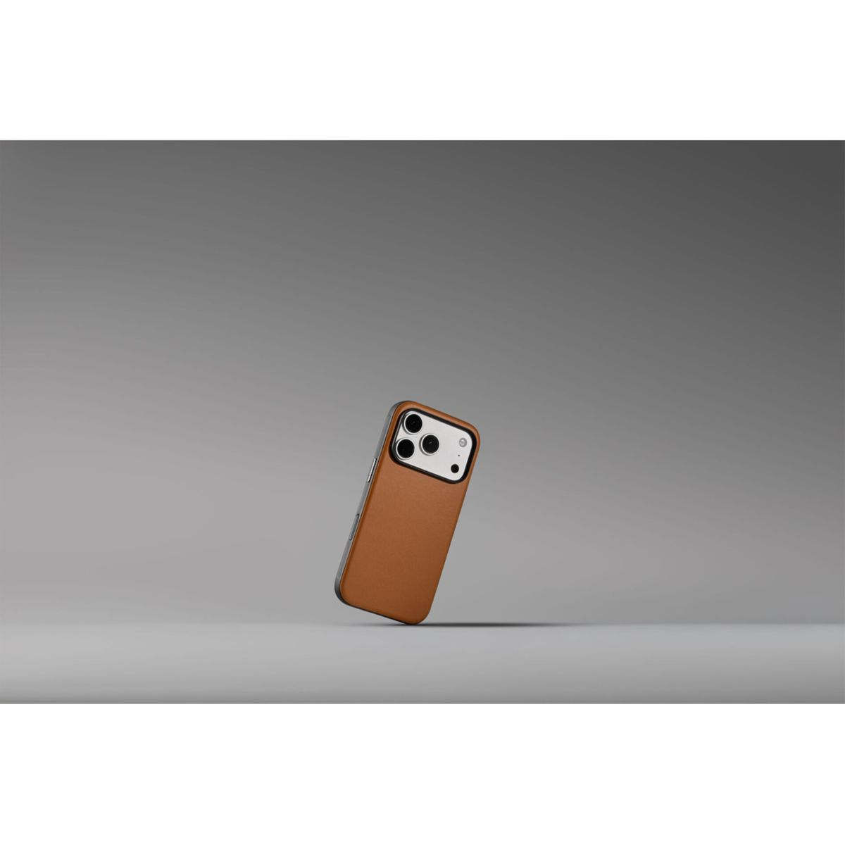 Uno smartphone marrone con tripla fotocamera poggia su una superficie grigia con sfondo grigio.
