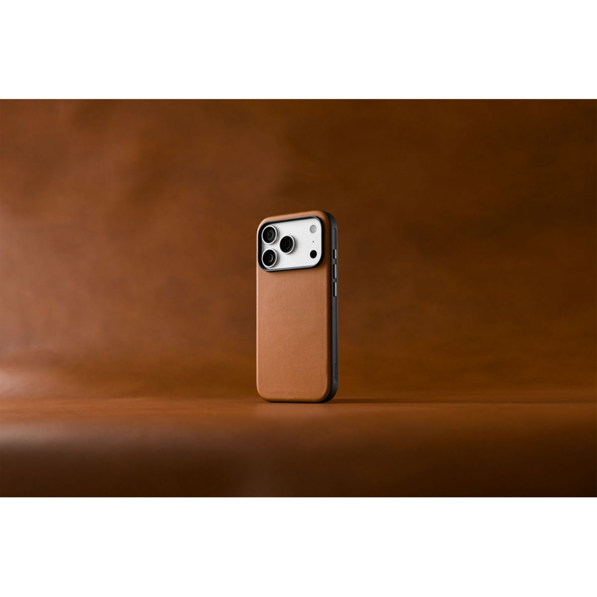Ein braunes Smartphone mit Lederhülle steht aufrecht auf einer braunen Lederoberfläche vor entsprechendem Hintergrund.