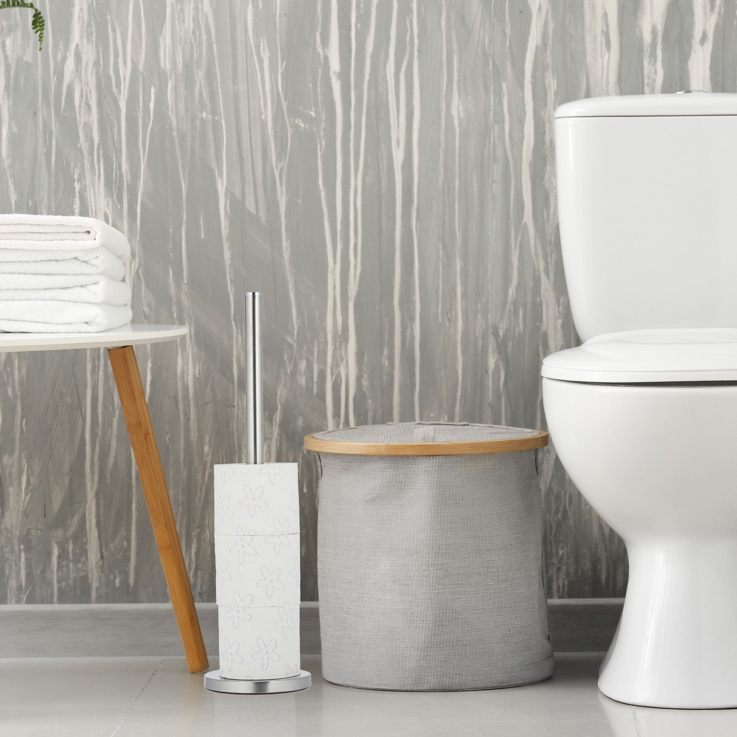 Ein Badezimmer mit weißer Toilette, grauem Wäschekorb, Toilettenpapierhalter und Handtüchern.
