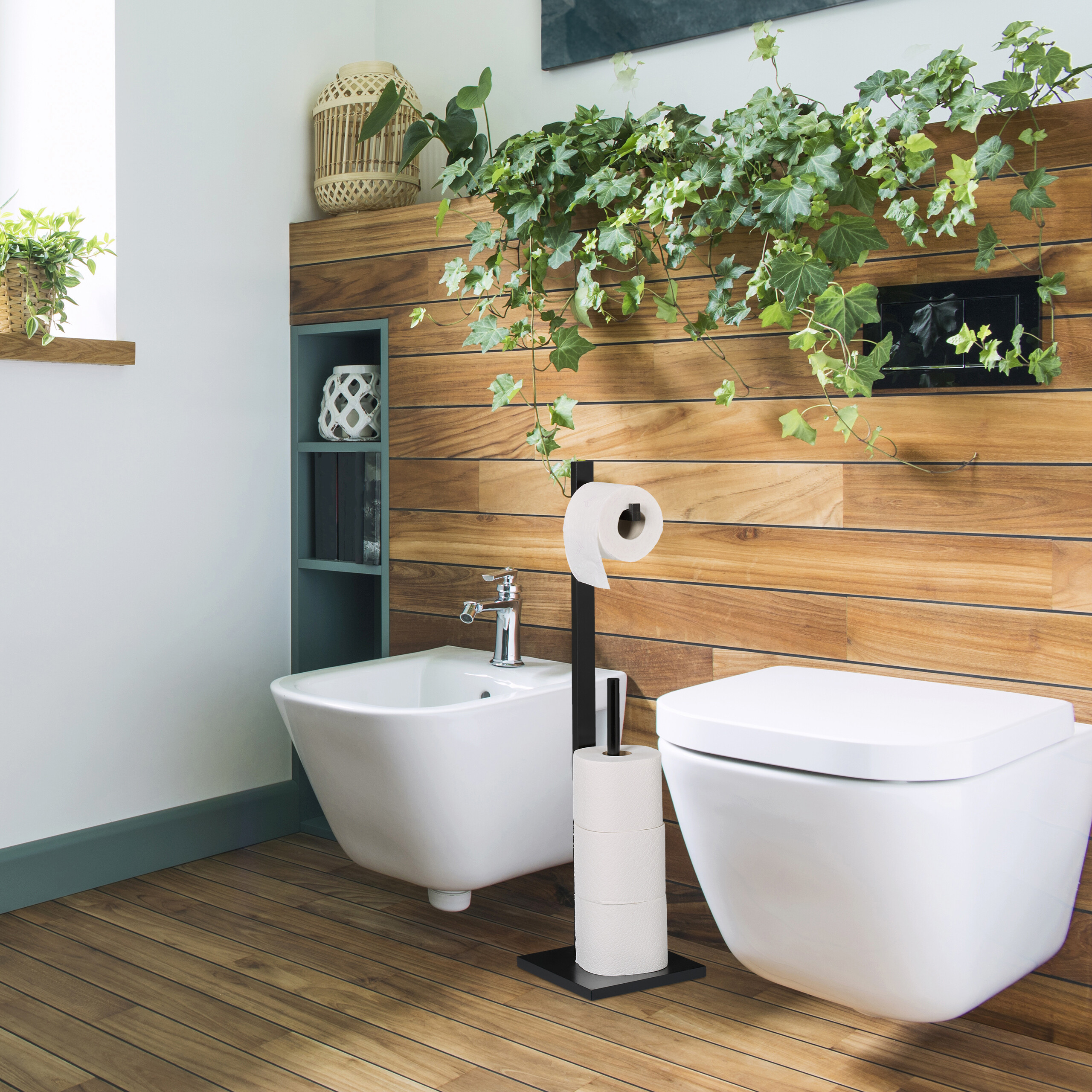 Badezimmer mit hängendem WC und Bidet vor einer Holzpaneelwand mit üppigen grünen Pflanzen und Toilettenpapierhalter.