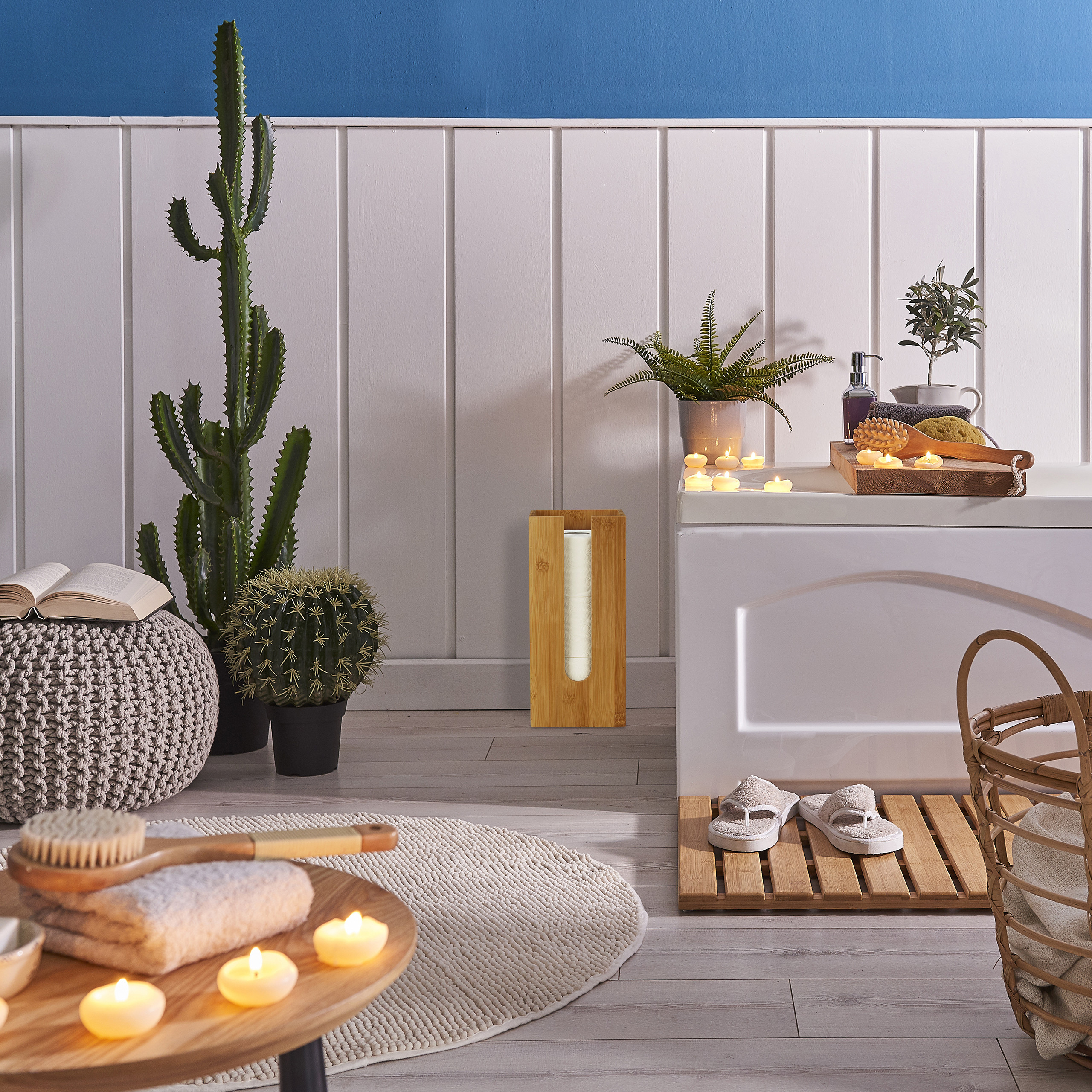 Gemütliches Badezimmer mit Pflanzen, brennenden Kerzen, einer Badewanne, einem Hocker mit Buch und Holzaccessoires.