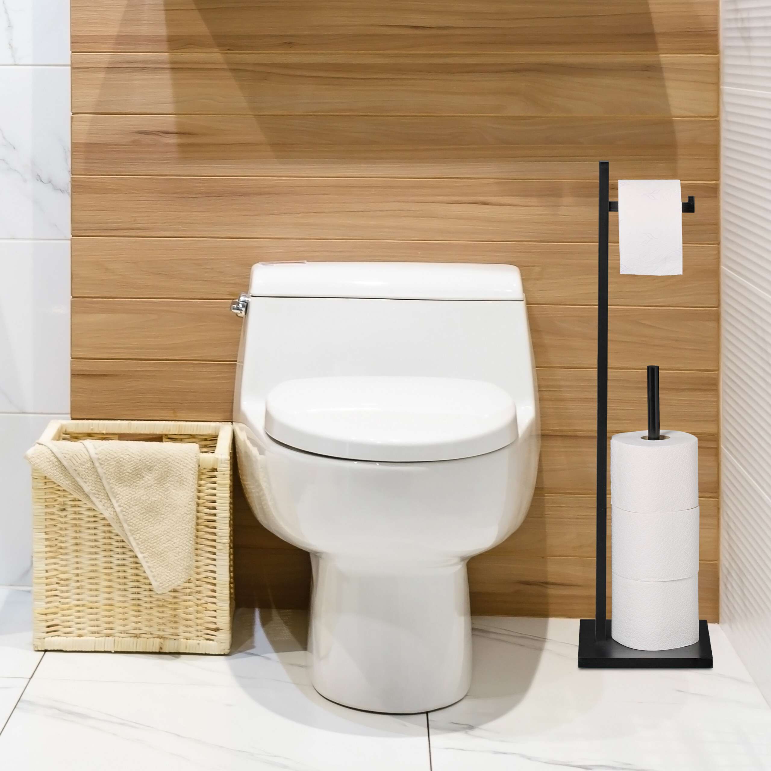 Eine weiße Toilette steht vor einer holzverkleideten Wand, daneben ein Korb mit Tuch und ein schwarzer Toilettenpapierhalter.