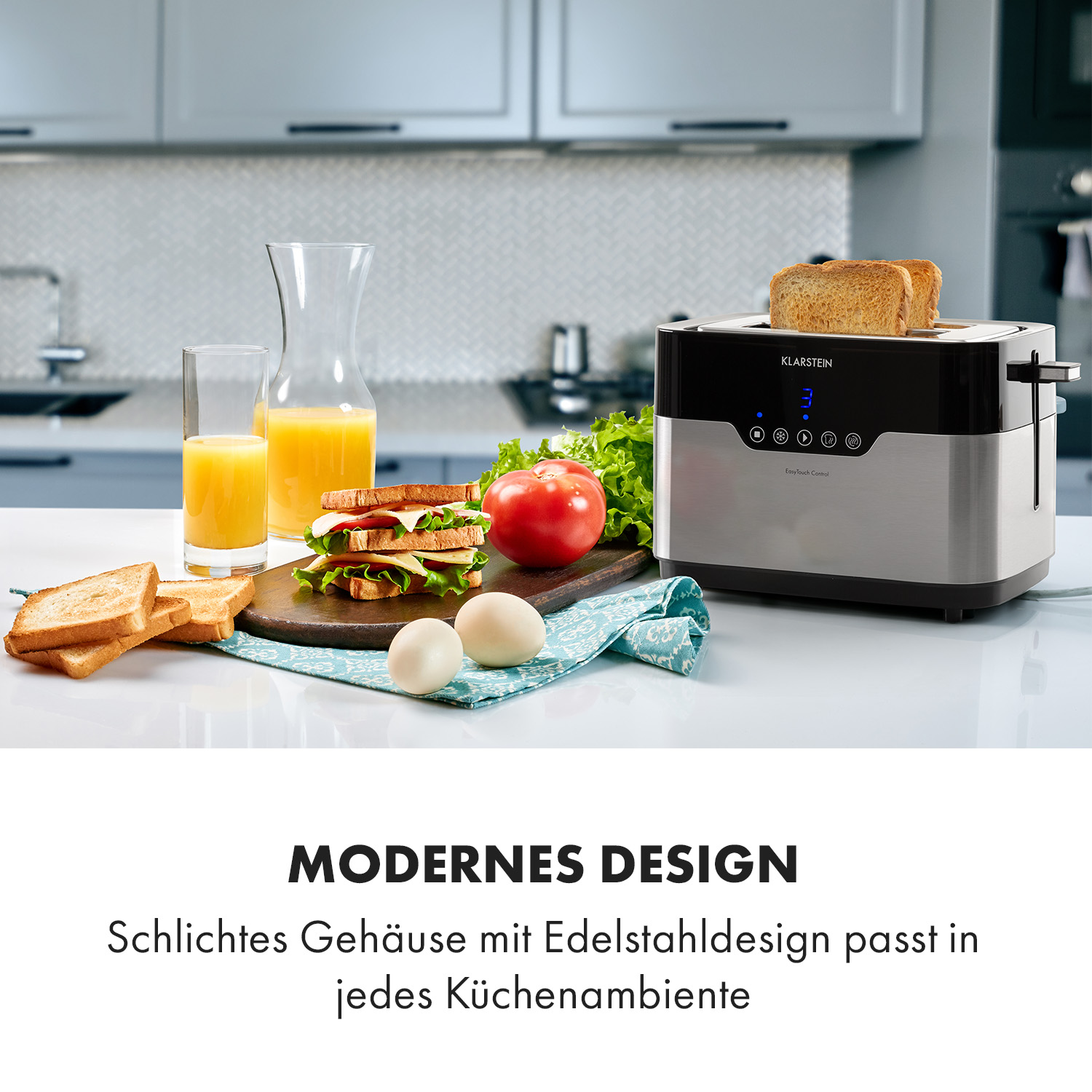 Moderner Toaster mit Toastbrot, Orangensaft, Sandwich, Eiern und Tomate auf einer Küchentheke.