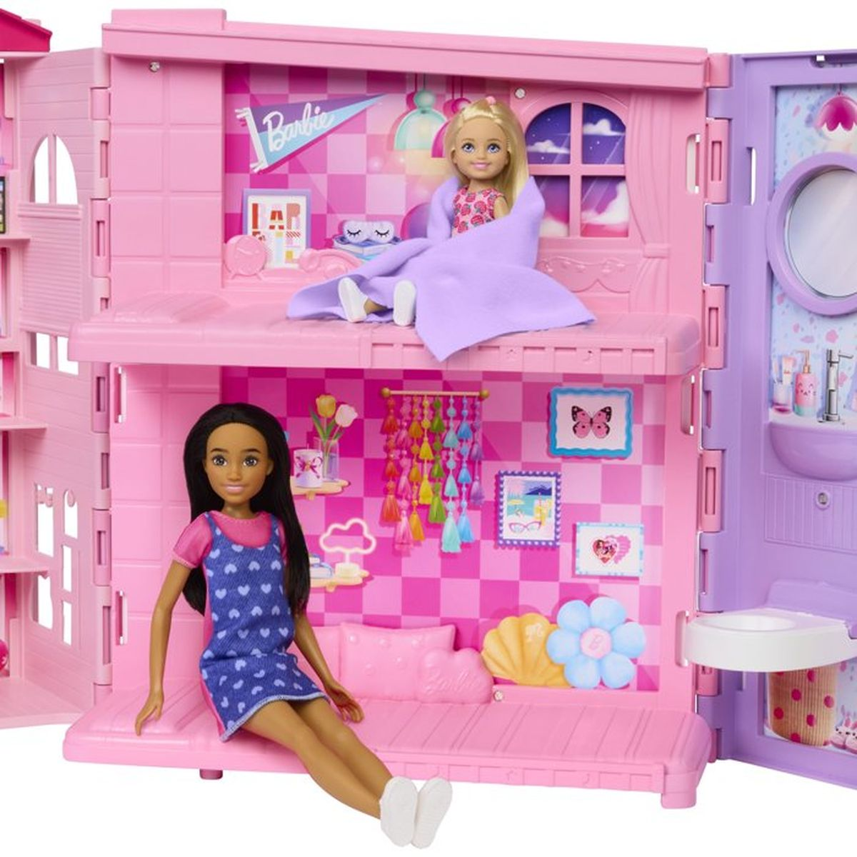 Zwei Barbie-Puppen in einem zweistöckigen, rosa Puppenhaus mit Schlaf- und Badezimmer.