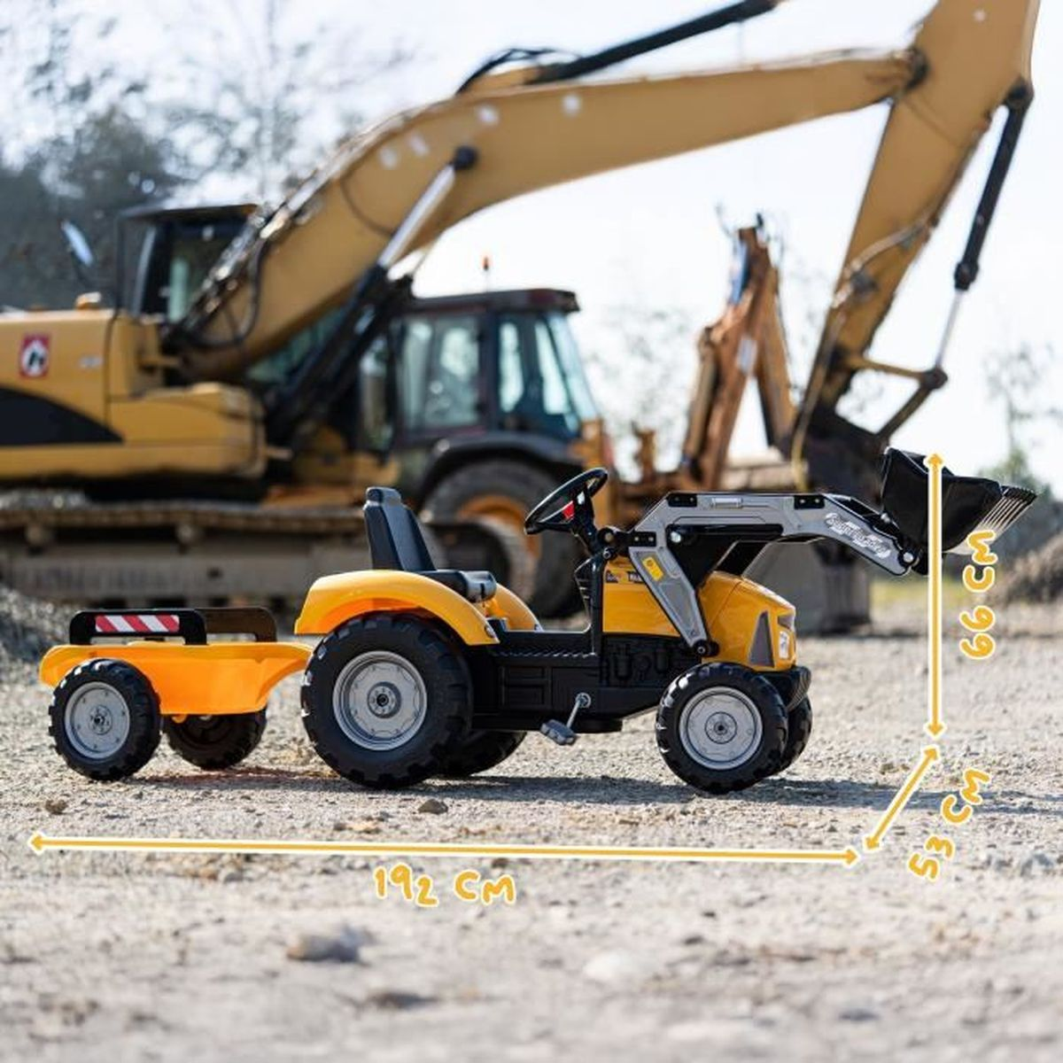 Ein gelber Spielzeugtraktor mit Anhänger steht im Vordergrund, dahinter ein echter Bagger.