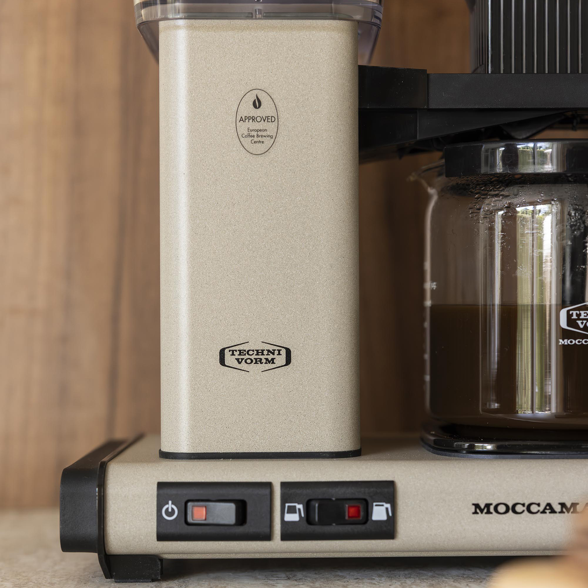 Gros plan sur une cafetière Technivorm Moccamaster beige avec une carafe en verre remplie de café.