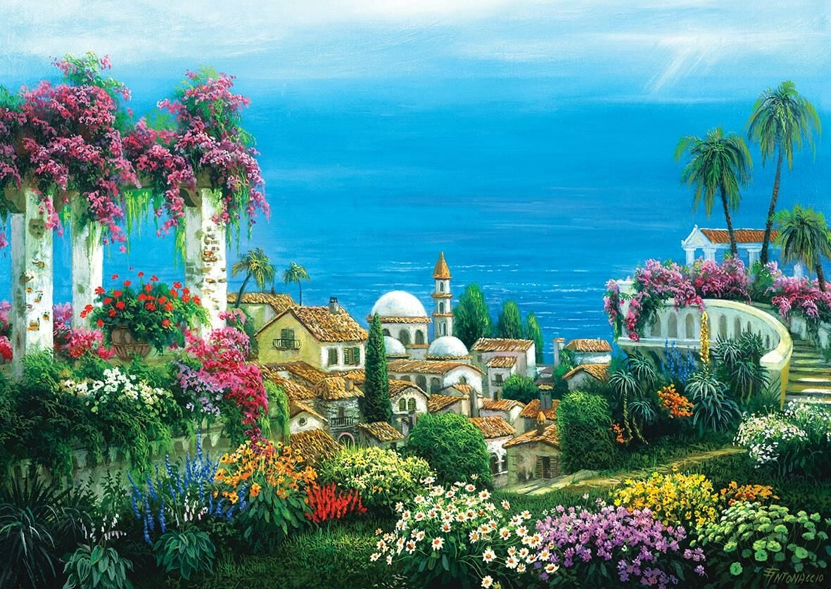 Canlı çiçekler, beyaz binalar ve arka planda mavi bir deniz ile renkli bir Akdeniz kıyı kasabası.