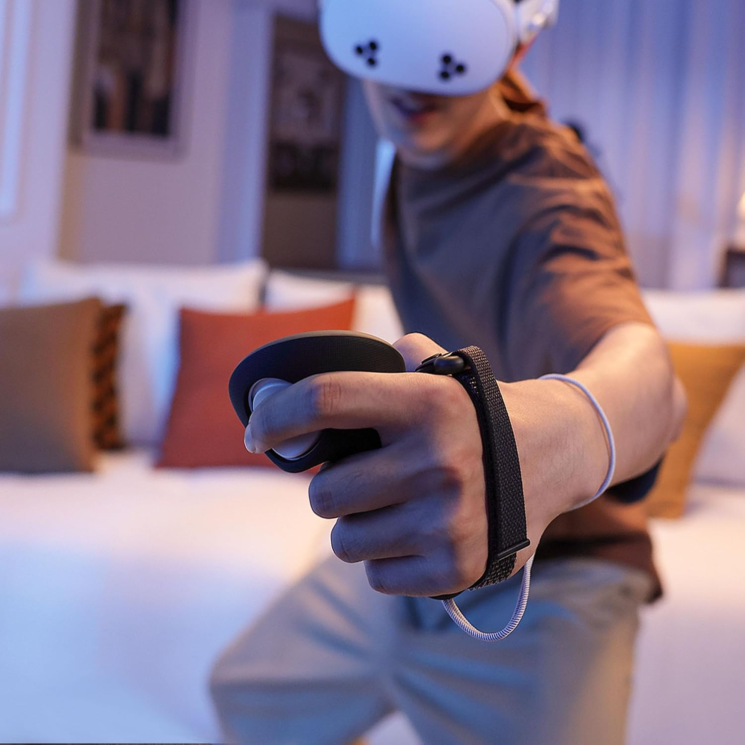 Eine Person mit VR-Headset hält einen VR-Controller in einer hellen Raum mit Sofa im Hintergrund.