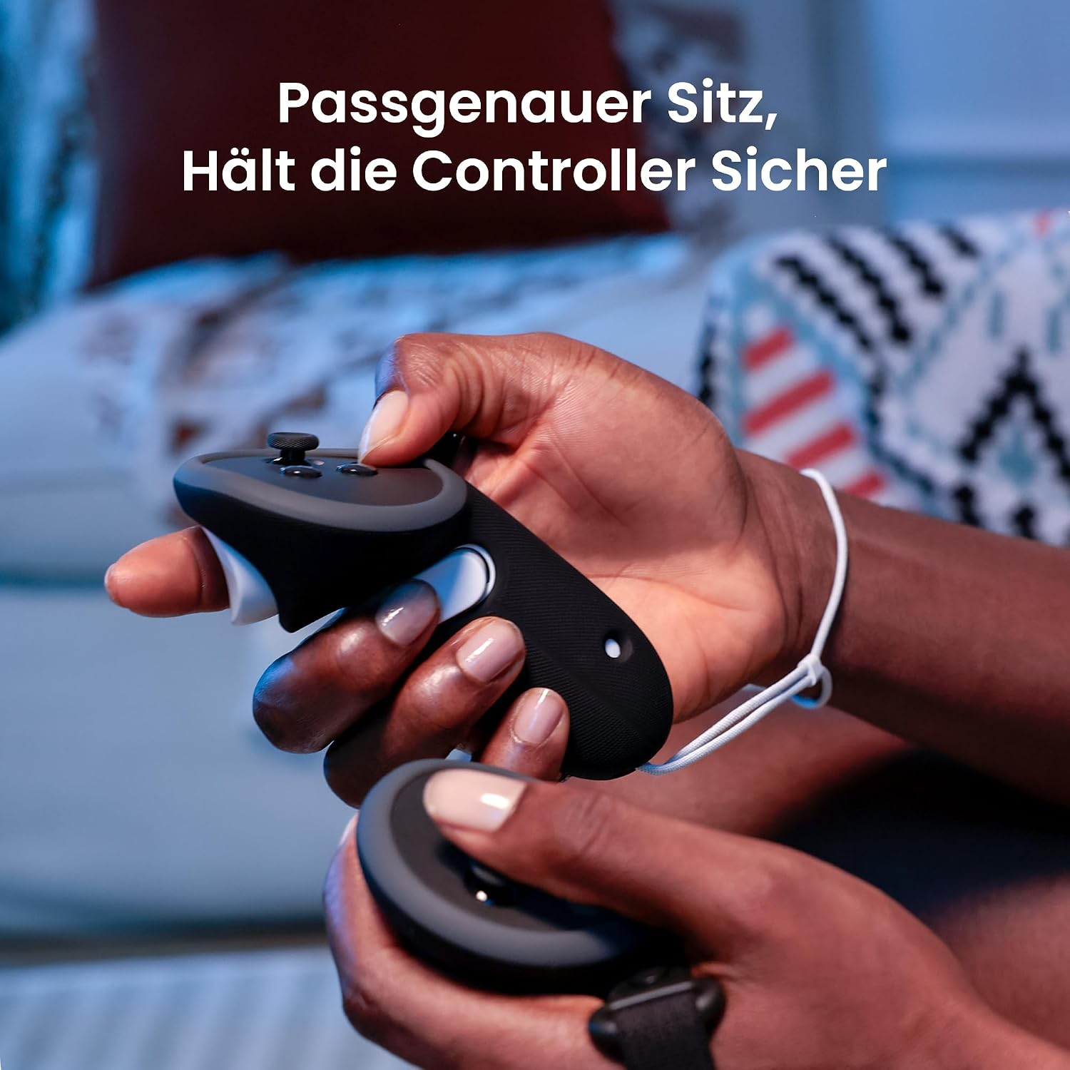 Hände halten schwarze VR-Controller mit Schutzhüllen in einem Zimmer mit Kissen im Hintergrund.