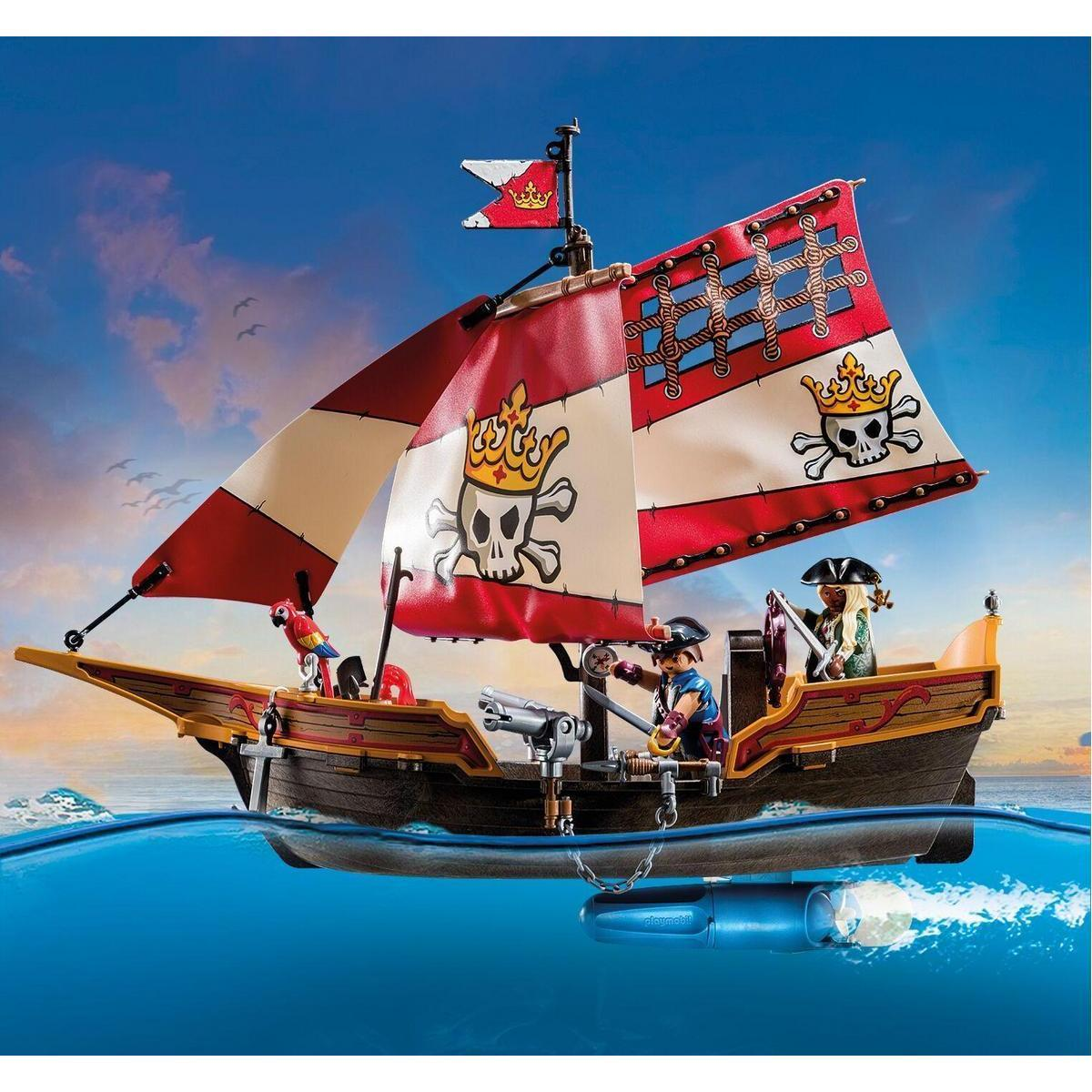 Barco pirata de Playmobil con velas, figuras y un motor submarino flotando en el agua bajo un cielo al atardecer.