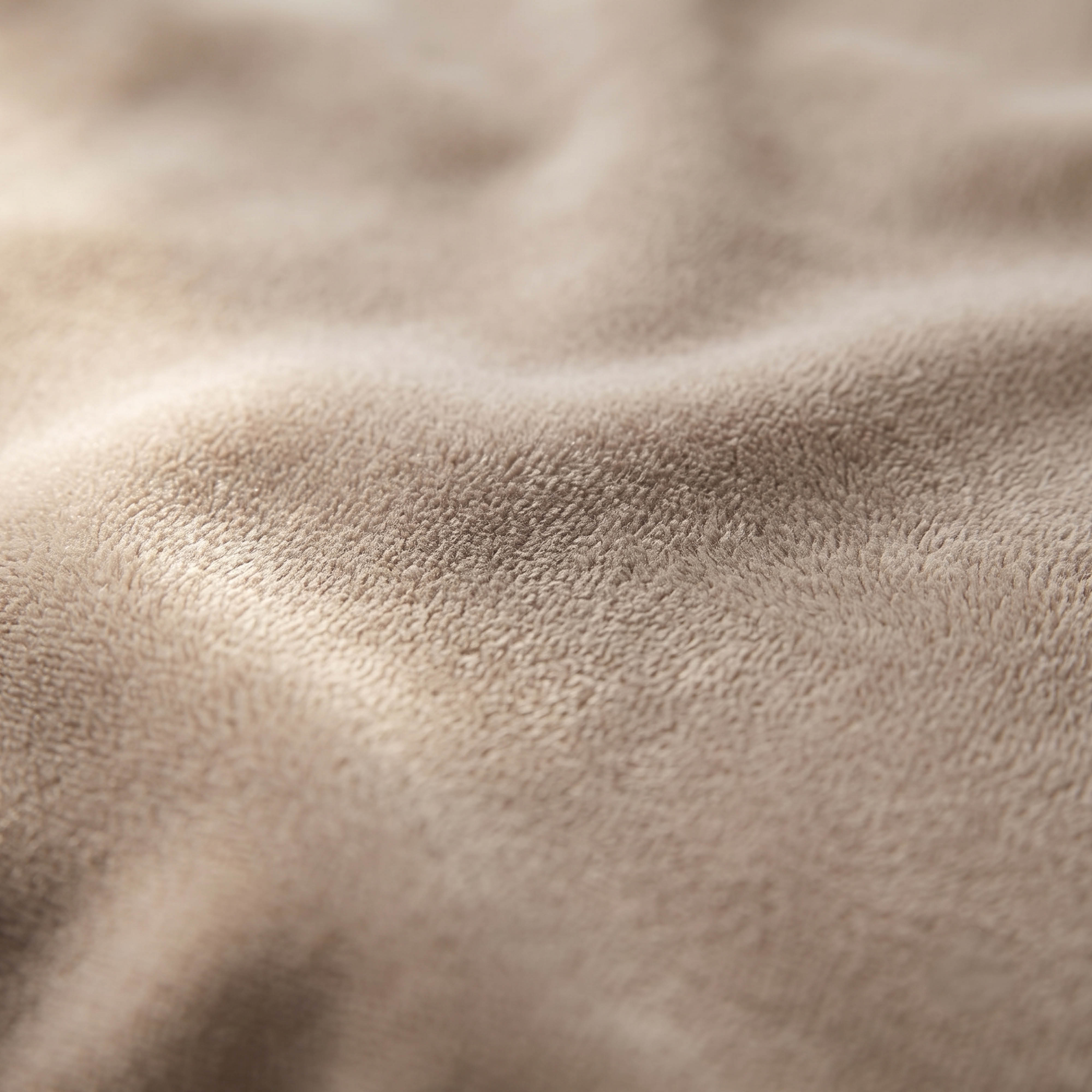 Couverture en peluche marron clair douce avec des plis.