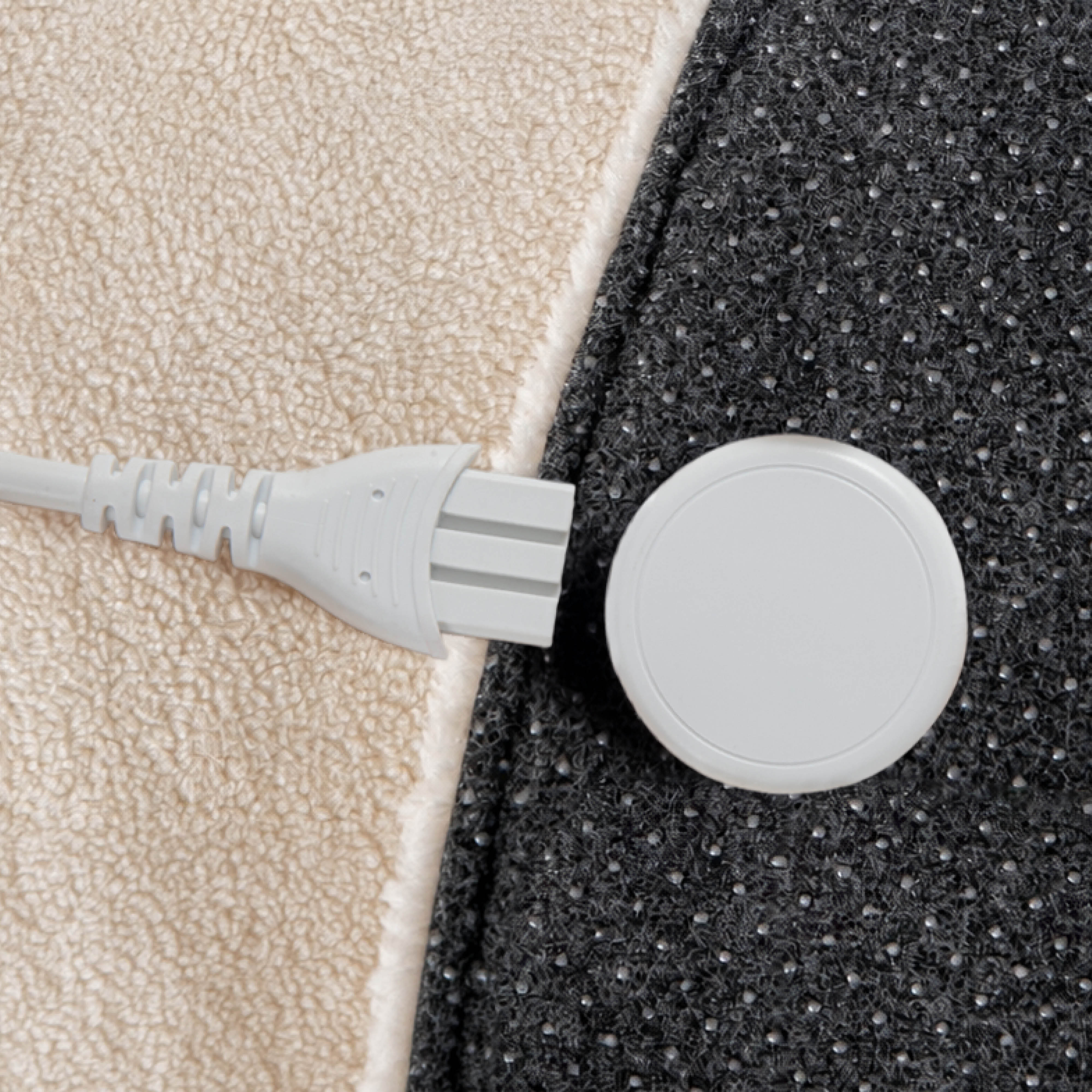 A white plug and a round button on beige and gray fabric.