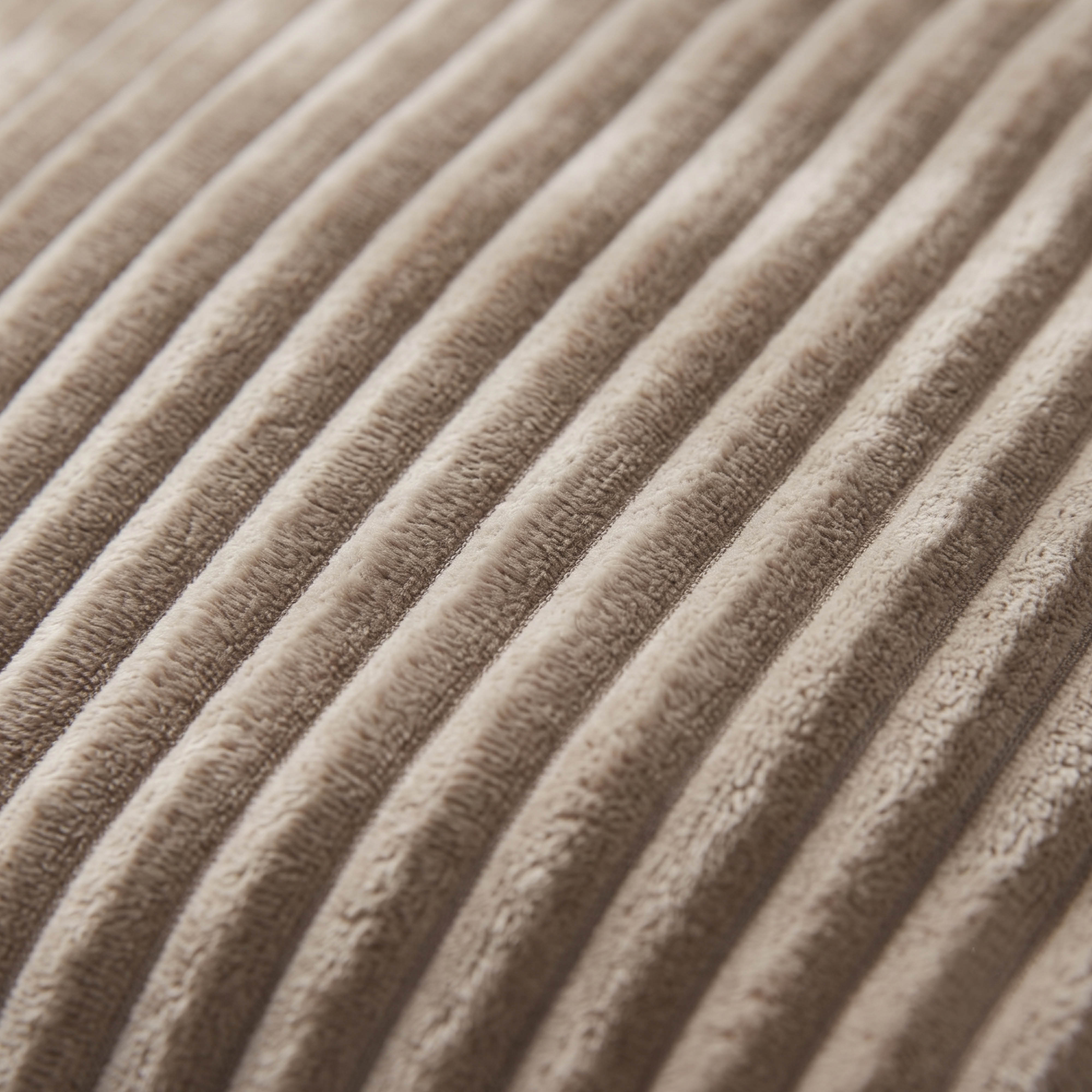 Gros plan sur une surface de tissu velours côtelé beige doux avec des rayures diagonales.