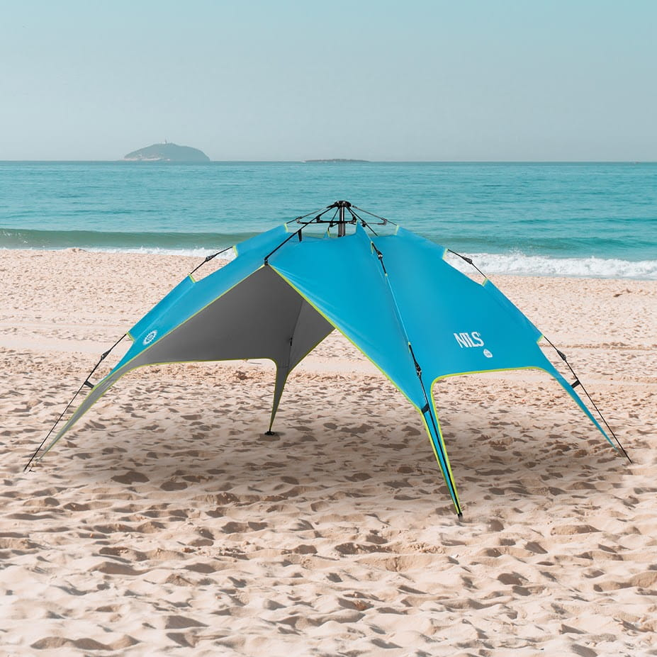Niebieski namiot plażowy stoi na piaszczystej plaży nad morzem pod czystym niebem.