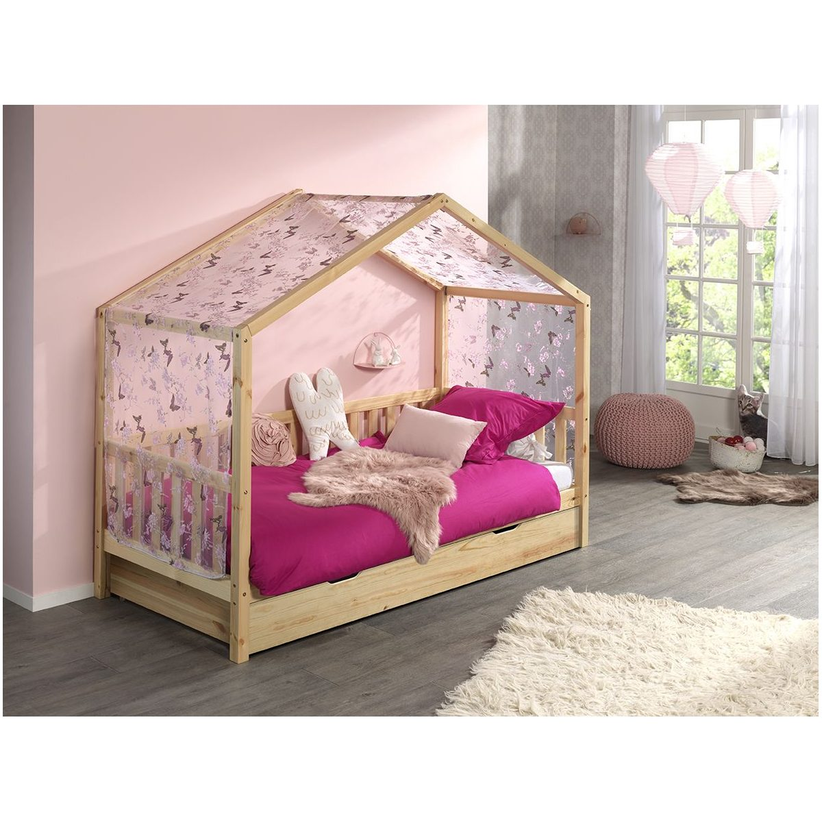 Ein hölzernes Hausbett mit pinkem Baldachin, Kissen und Decke in einem rosafarbenen Kinderzimmer mit Holzboden.