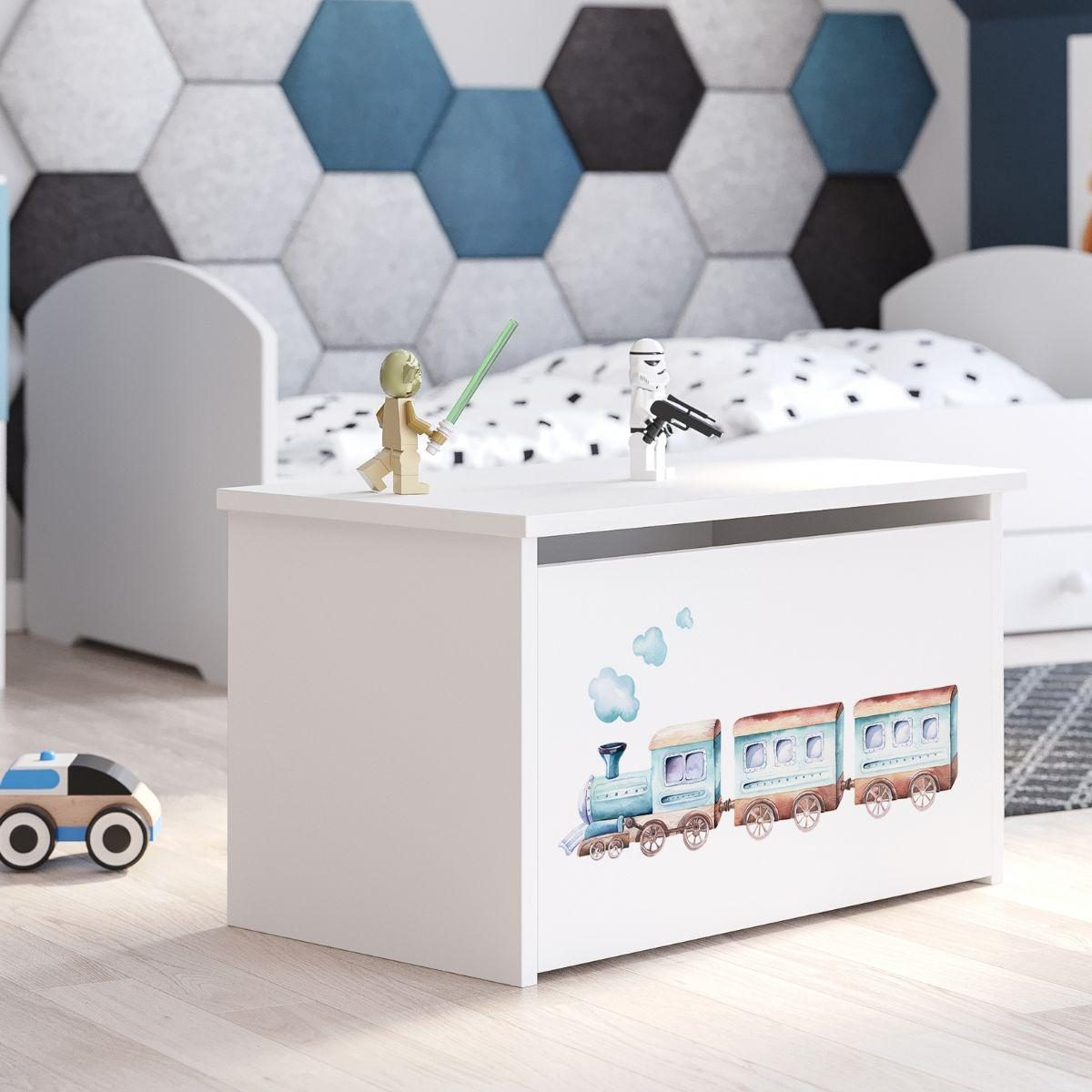 Eine weiße Spielzeugkiste mit einem blauen Zugmotiv steht in einem Kinderzimmer vor einem grauen und blauen Hexagon-Wandmuster.