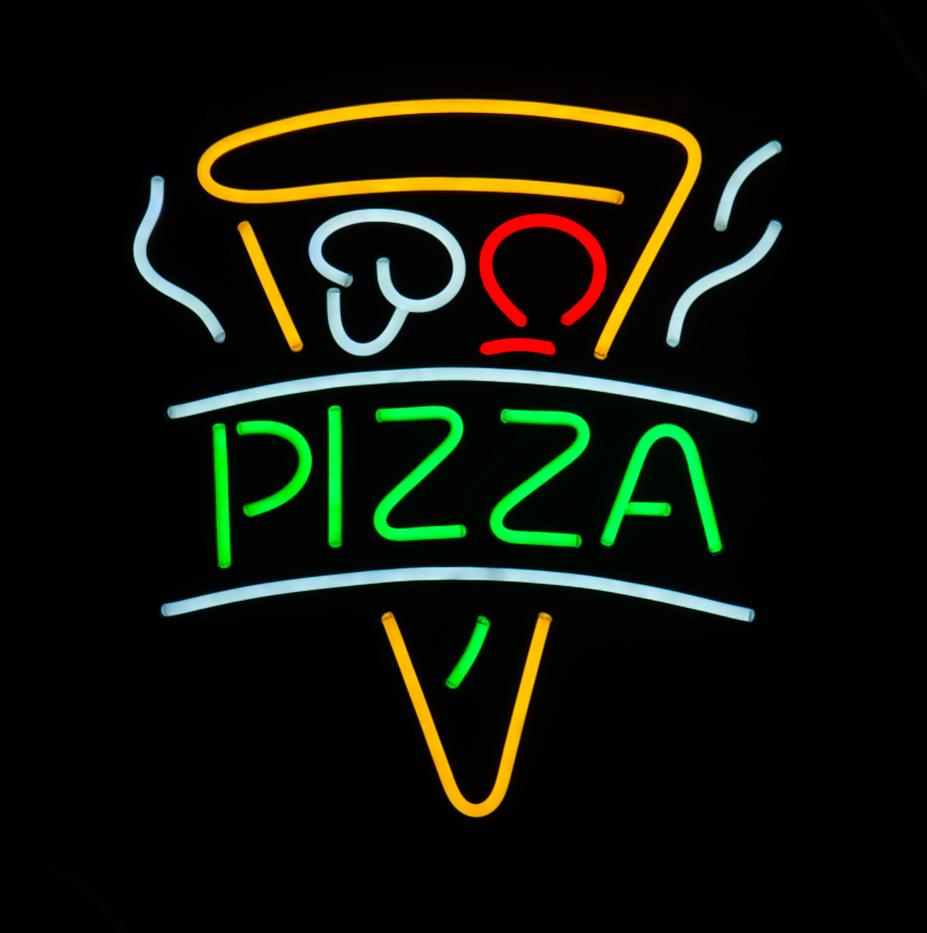 Ein farbiges Neonschild zeigt eine Pizzaslice mit dem grünen Schriftzug PIZZA auf schwarzem Hintergrund.