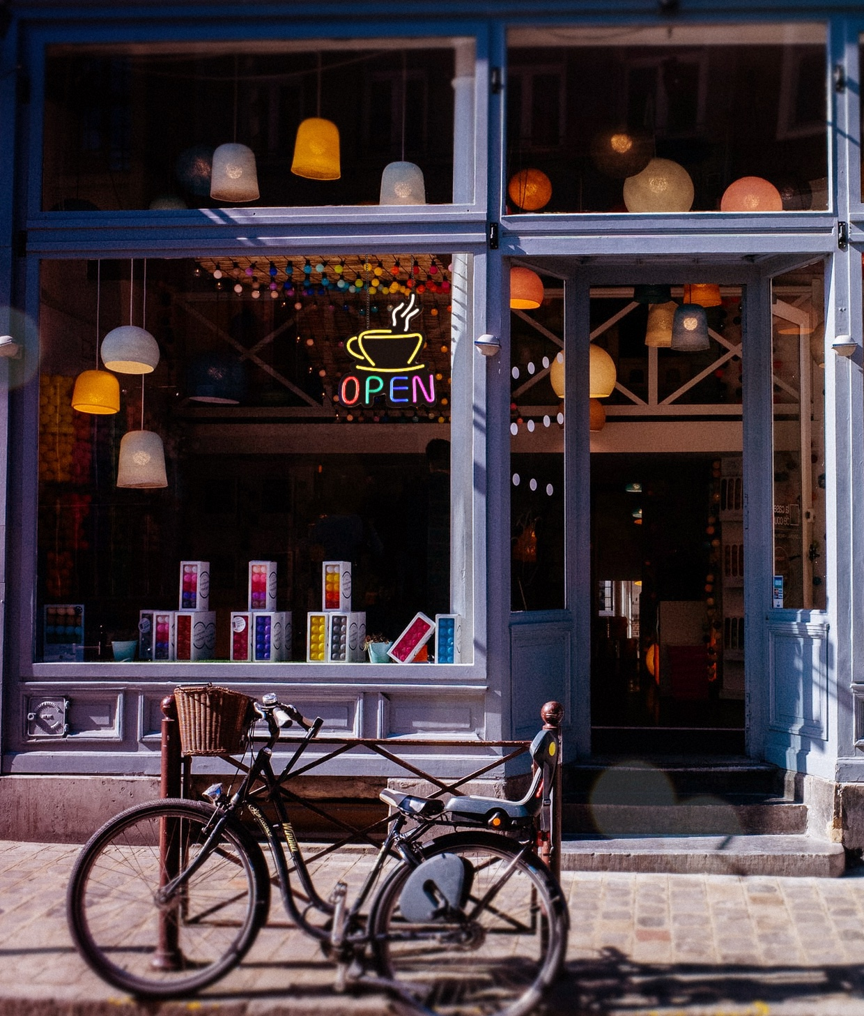 Ein gemütliches Café mit einer leuchtenden Open-Neonreklame im Fenster und einem Fahrrad davor.