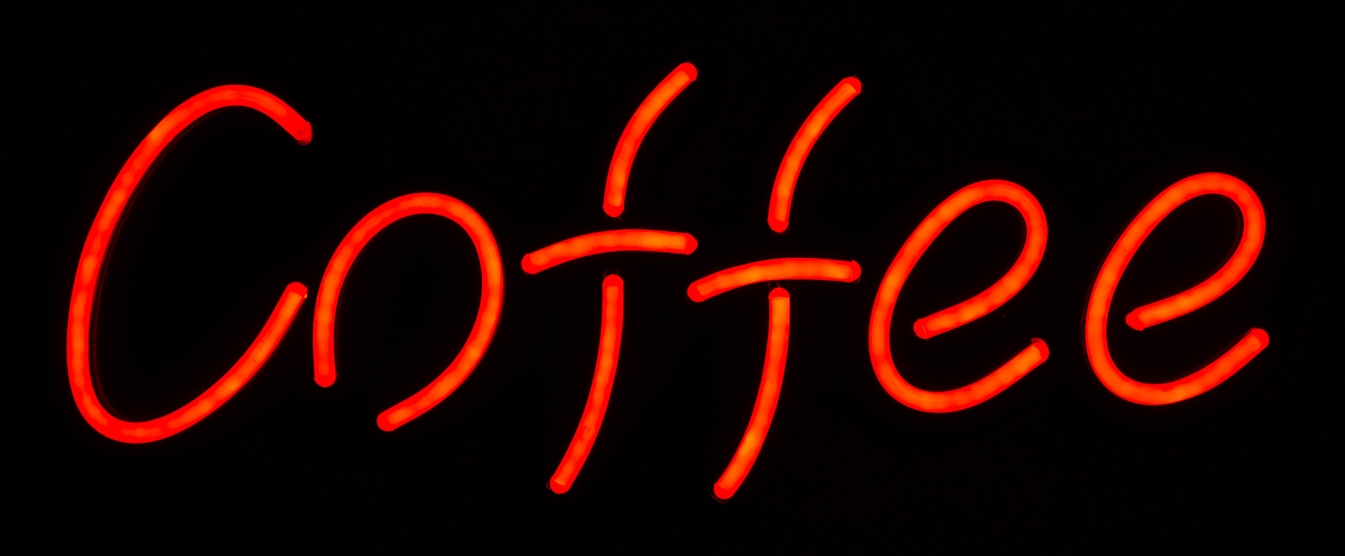 Ein rotes Neonschild mit der Aufschrift Coffee auf schwarzem Hintergrund.