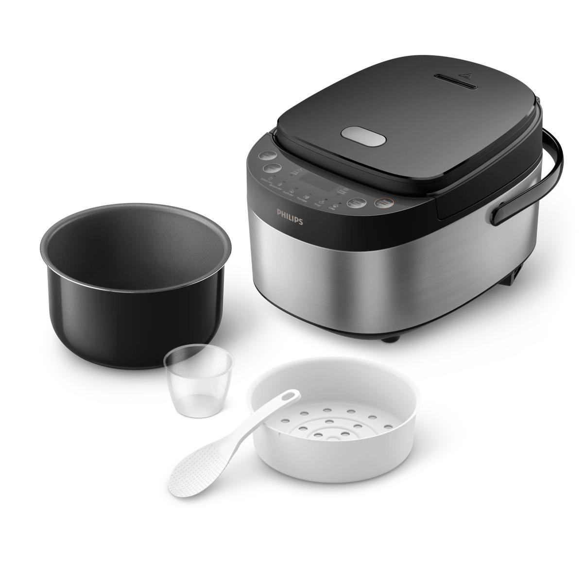 Ein Philips Multikocher mit Innentopf, Messbecher, weißem Dampfkorb und Reislöffel auf weißer Oberfläche.