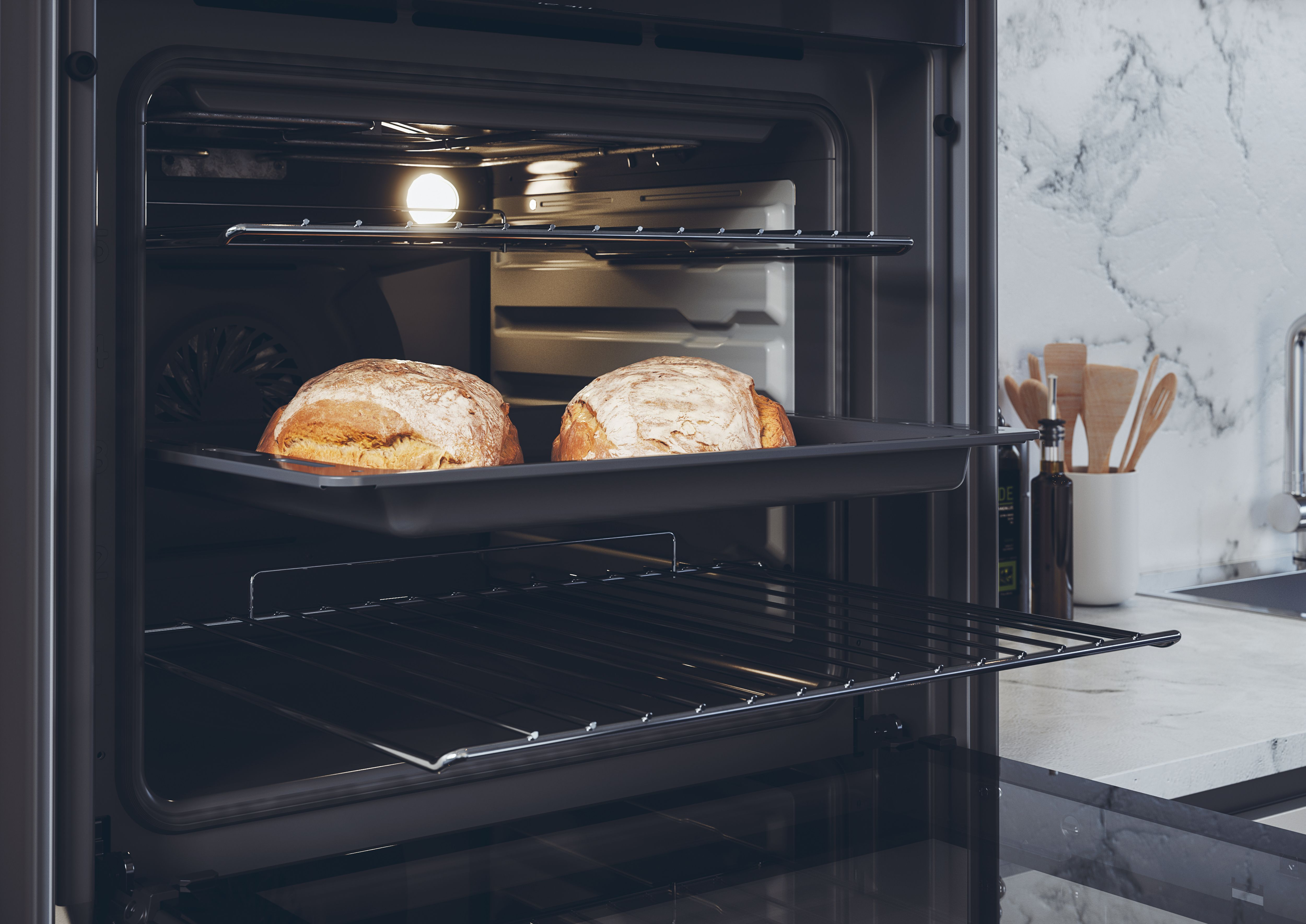 Due pagnotte cuociono su una teglia nel forno illuminato.