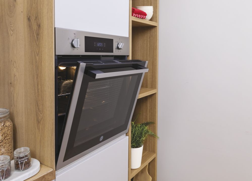 Un forno da incasso in acciaio inossidabile con la porta in vetro leggermente aperta in un mobile da cucina.