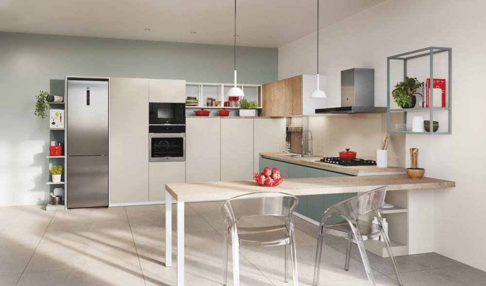 Cucina moderna con mobili beige, elettrodomestici in acciaio, isola in legno e sedie trasparenti.