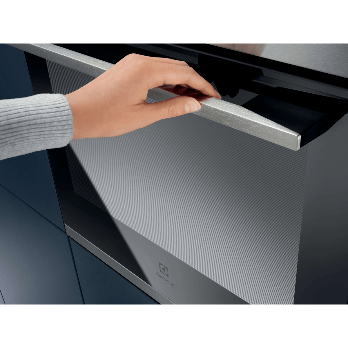 Una mano che apre la porta di un moderno forno Electrolux con maniglia argentata.