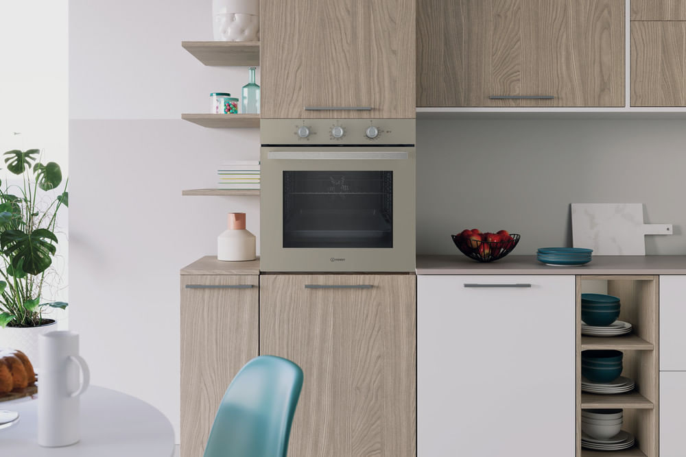 Cucina moderna con mobili in legno, forno chiaro, mobile bianco, cesto di frutta e piante.
