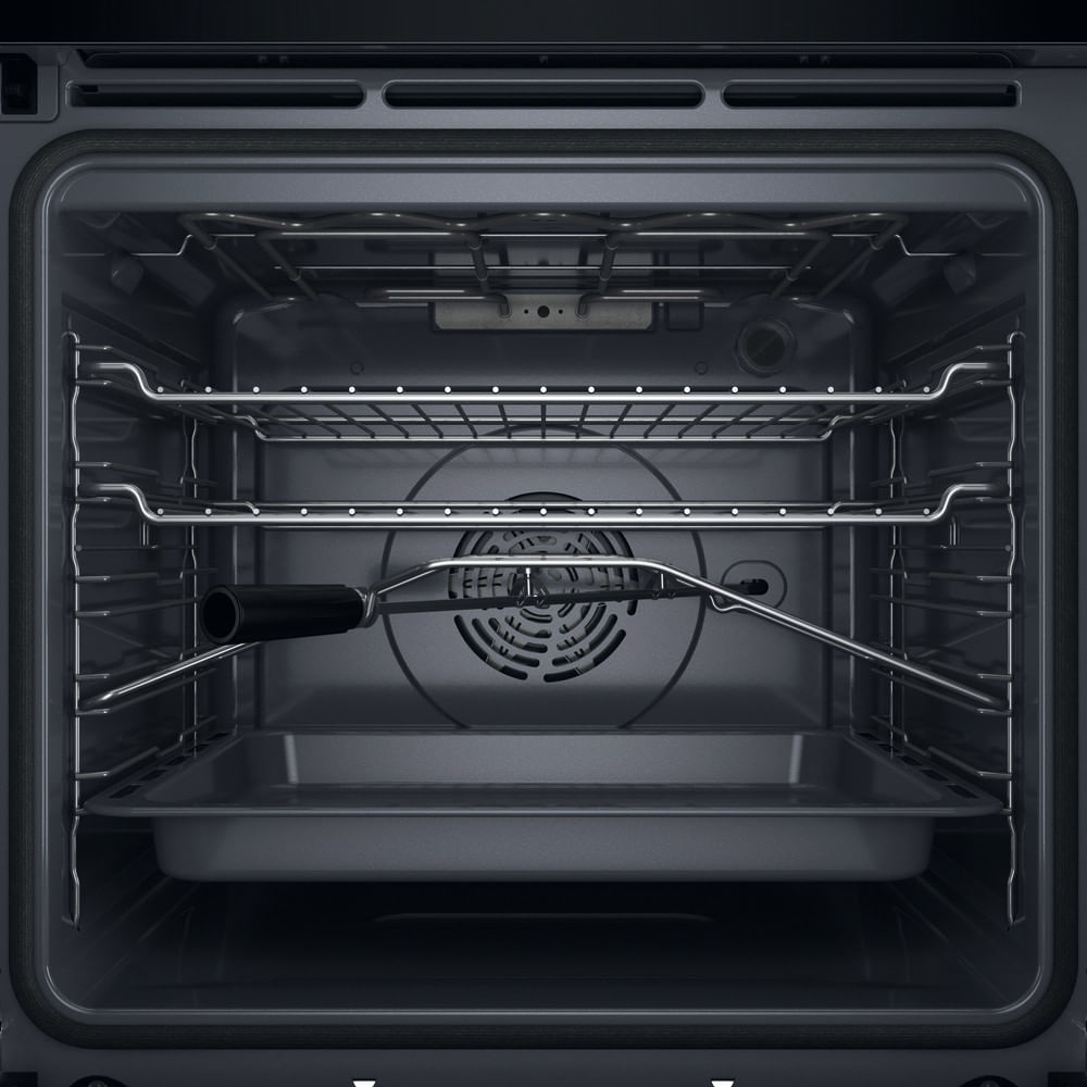 Vista interna di un forno vuoto con griglie, una teglia sul fondo e uno spiedo.