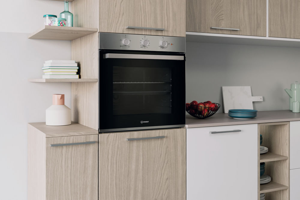 Cucina moderna con mobili in legno, forno incassato, mensole e piano di lavoro con fruttiera e piatti.