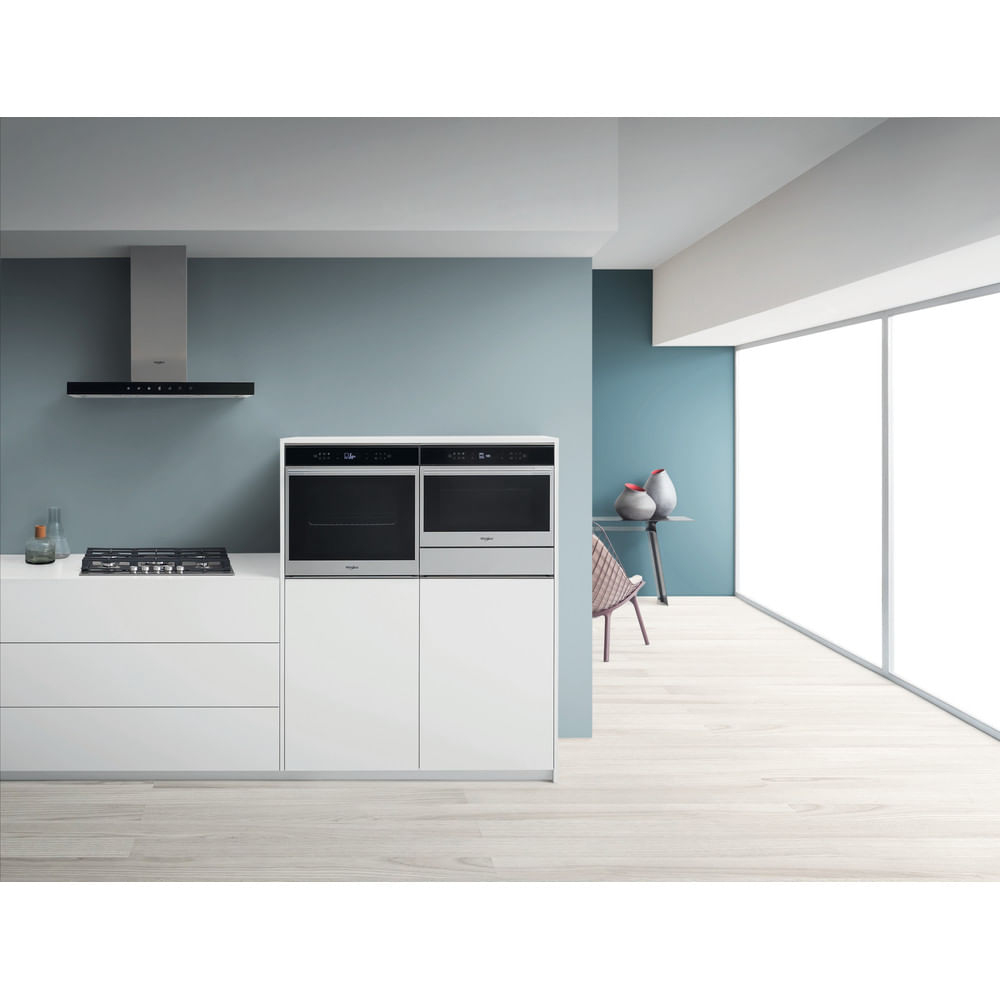 Cucina moderna con forni argentati incassati, piano cottura a gas, cappa aspirante e grandi finestre.