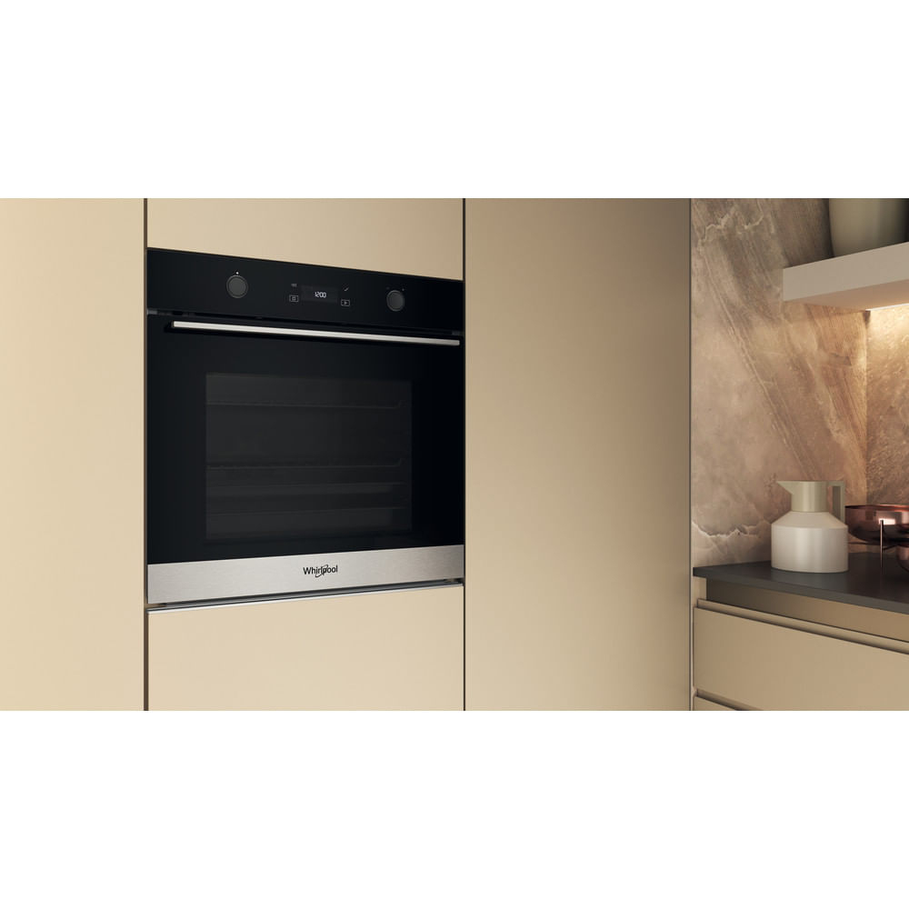 Un forno da incasso Whirlpool nero e acciaio inossidabile installato in mobili da cucina beige.
