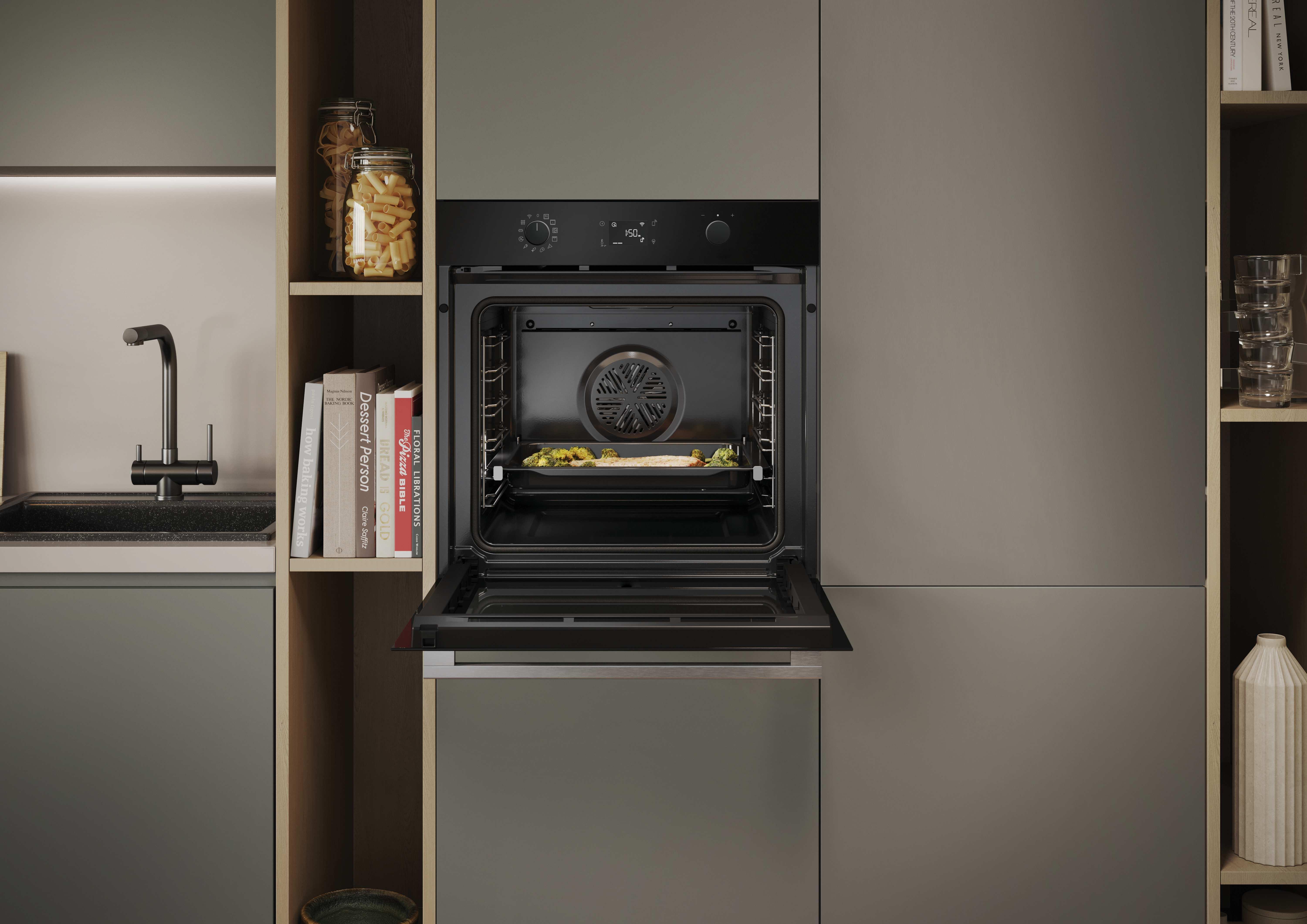 Moderna cucina grigia con forno aperto che cuoce cibo. Ripiani con libri e pasta a sinistra, bicchieri e vasi a destra.