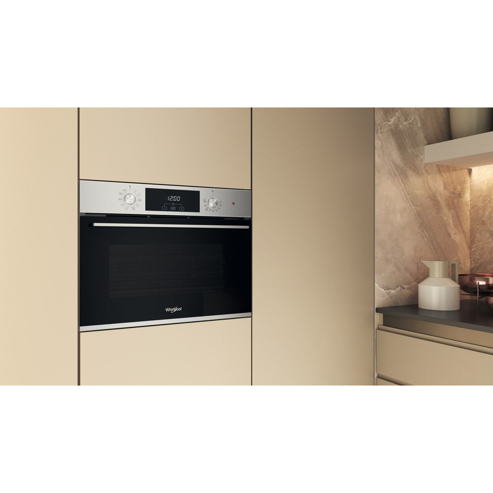 Un forno da incasso argentato con frontale in vetro nero e display digitale in una cucina moderna.