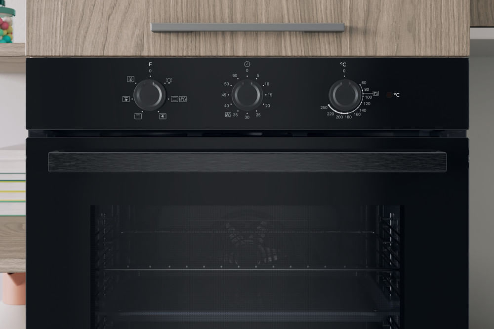 Un forno da incasso nero con tre manopole di controllo sul pannello e un mobile in legno sopra.