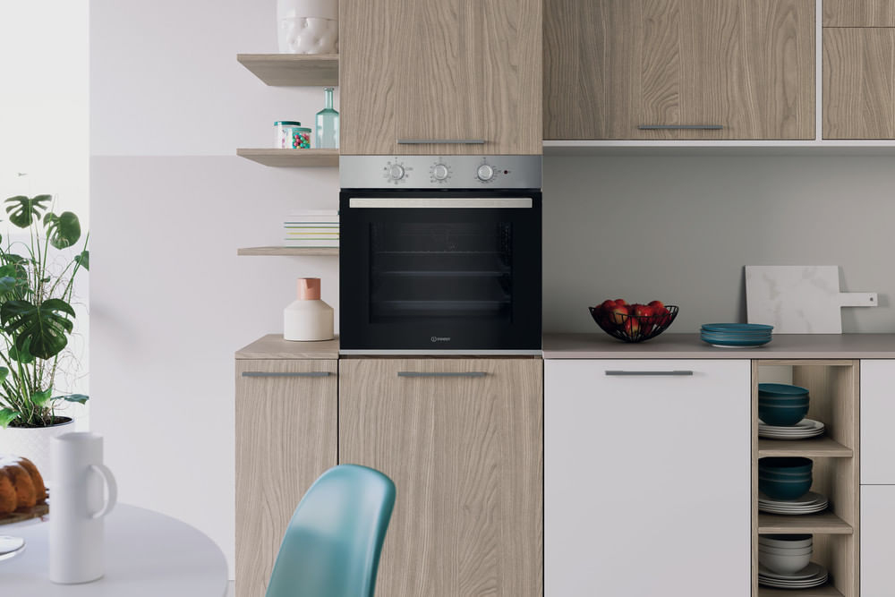 Cucina moderna con mobili in legno e bianchi, forno incassato, mensole decorate e ciotola di mele.