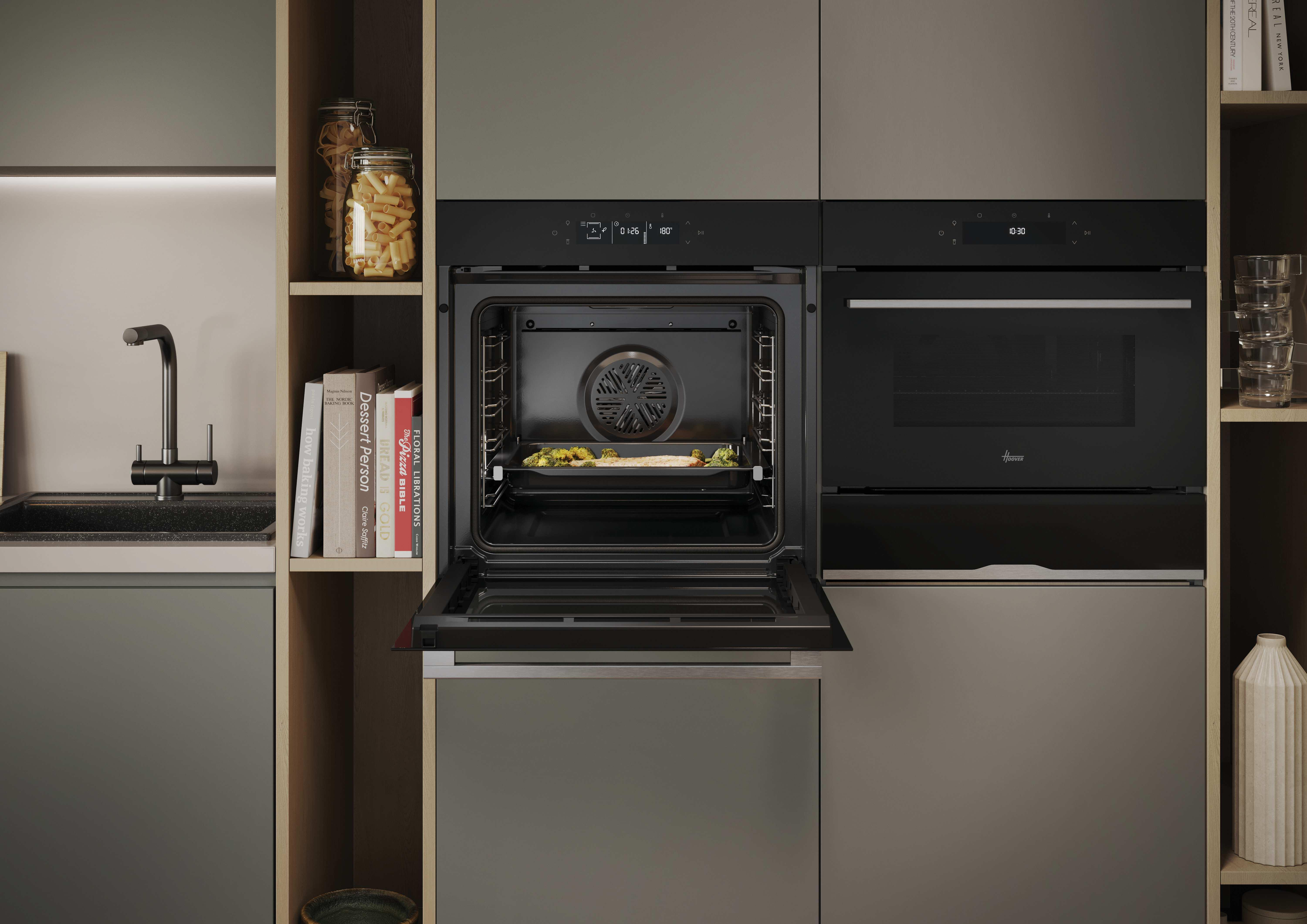 Moderna cucina con due forni neri da incasso; il forno a sinistra è aperto e cuoce cibo su una teglia.
