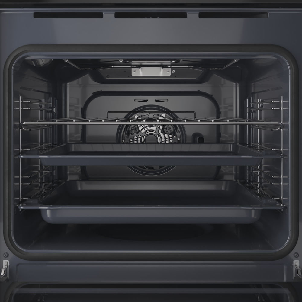Vista interna di un forno moderno con due teglie, una griglia e pareti scure.