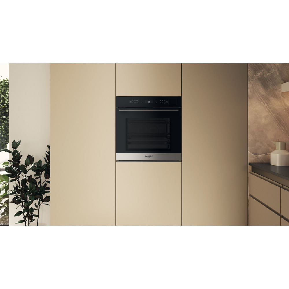 Moderno forno da incasso nero e acciaio inossidabile in mobili da cucina beige, con pianta a sinistra.