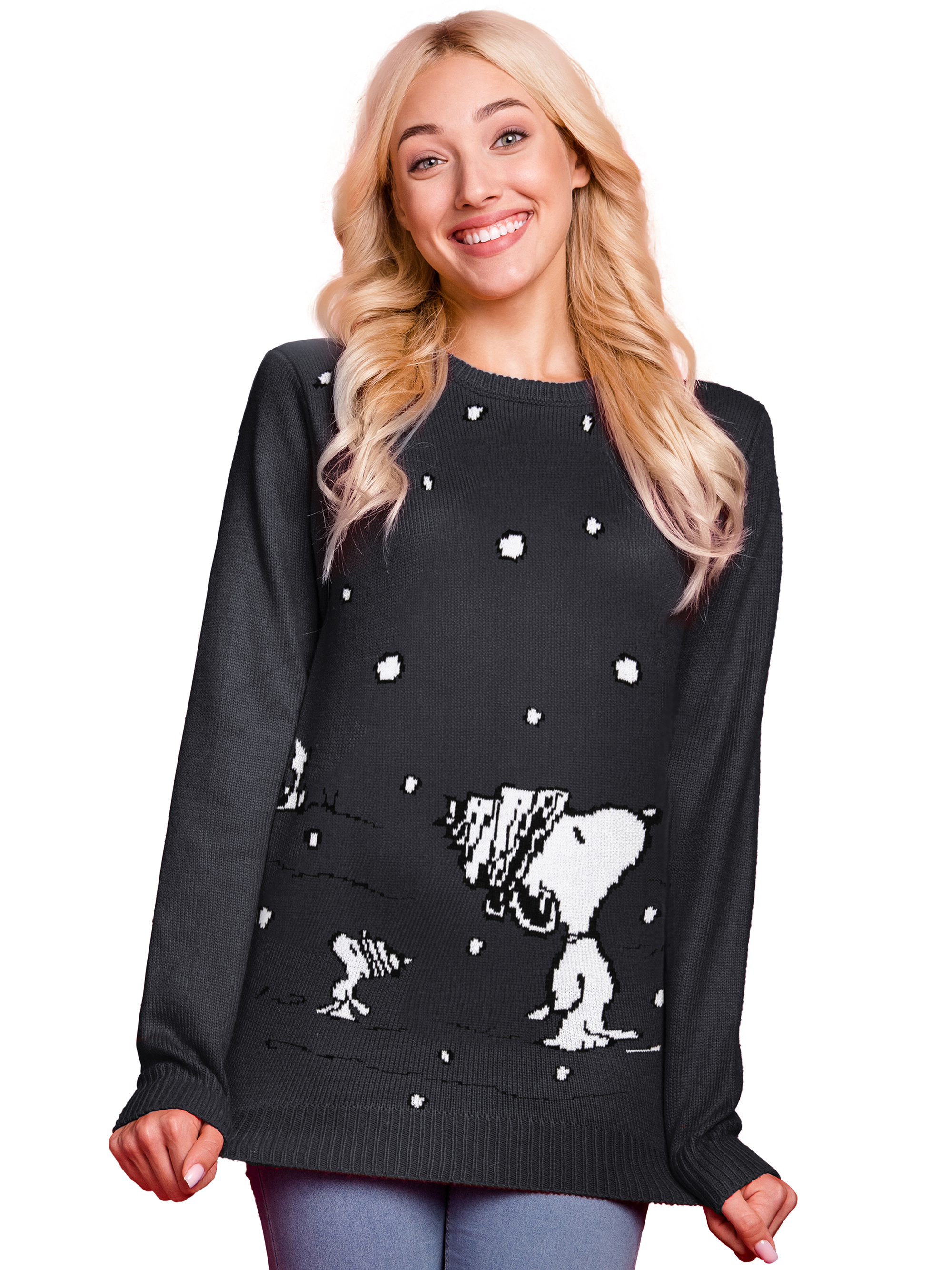 Blonde Frau lächelt in einem schwarzen Pullover mit weißem Snoopy-Muster vor weißem Hintergrund.