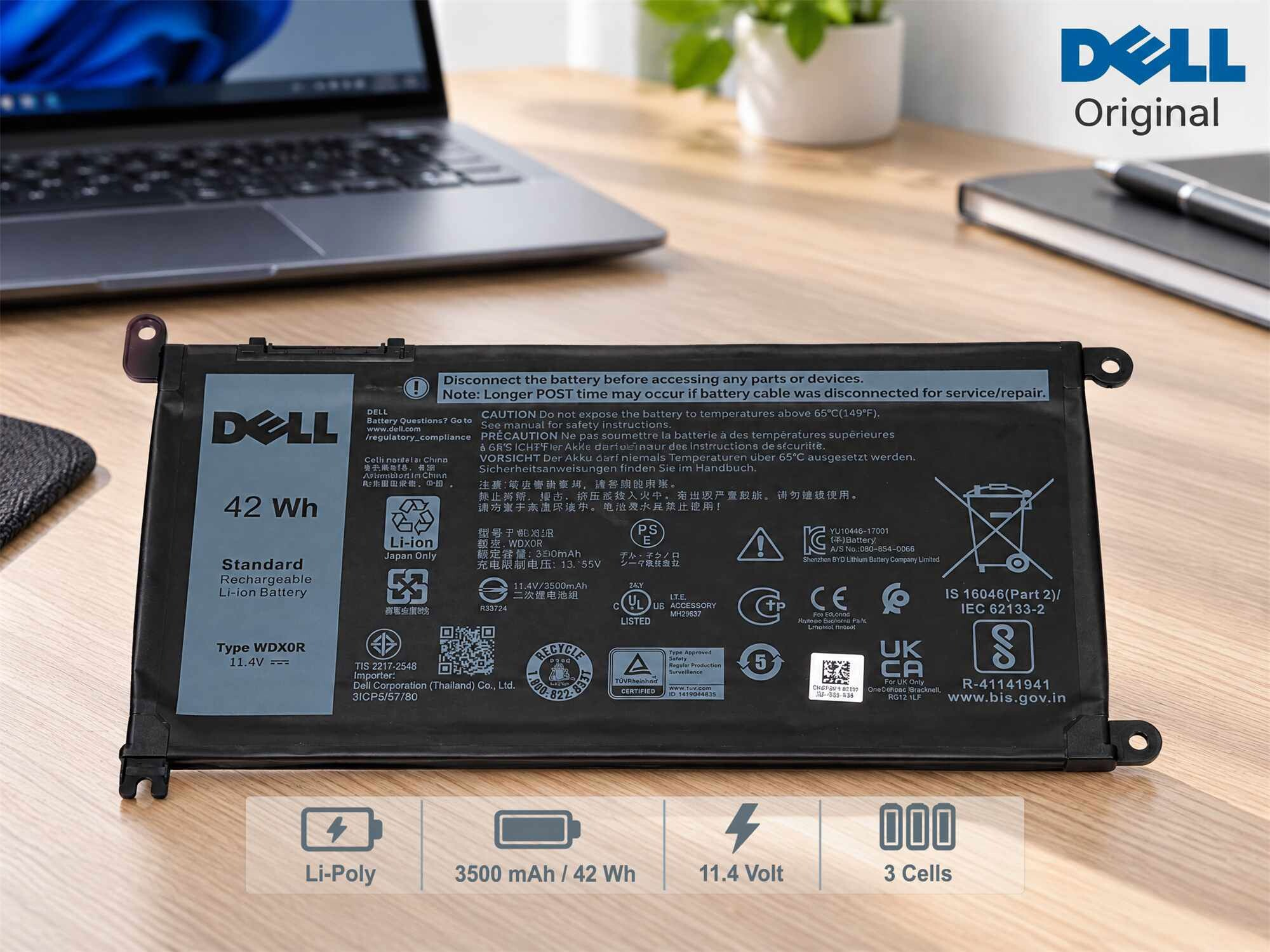 Dell-Laptop-Akku mit technischen Daten, Warnhinweisen und Sicherheitszeichen auf schwarzem Etikett vor Laptop.