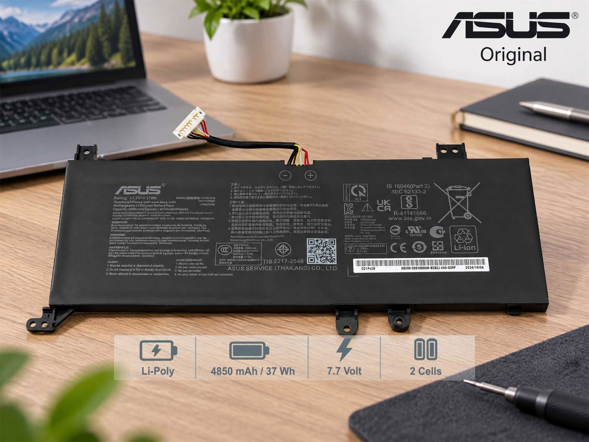 Schwarzer Asus Laptop-Akku auf holzfarbenem Tisch mit technischen Angaben und Kabel.