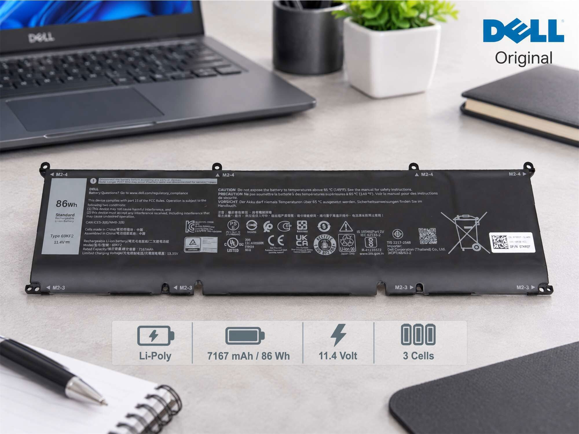Ein schwarzer Original-Dell-Laptop-Akku liegt auf einem Schreibtisch mit einem Stift und einer Notizbuch.