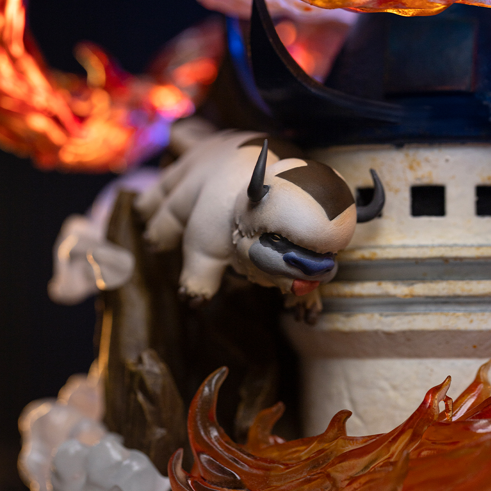 Una statuetta di Appa è appesa davanti a una struttura con effetti di fuoco sullo sfondo.