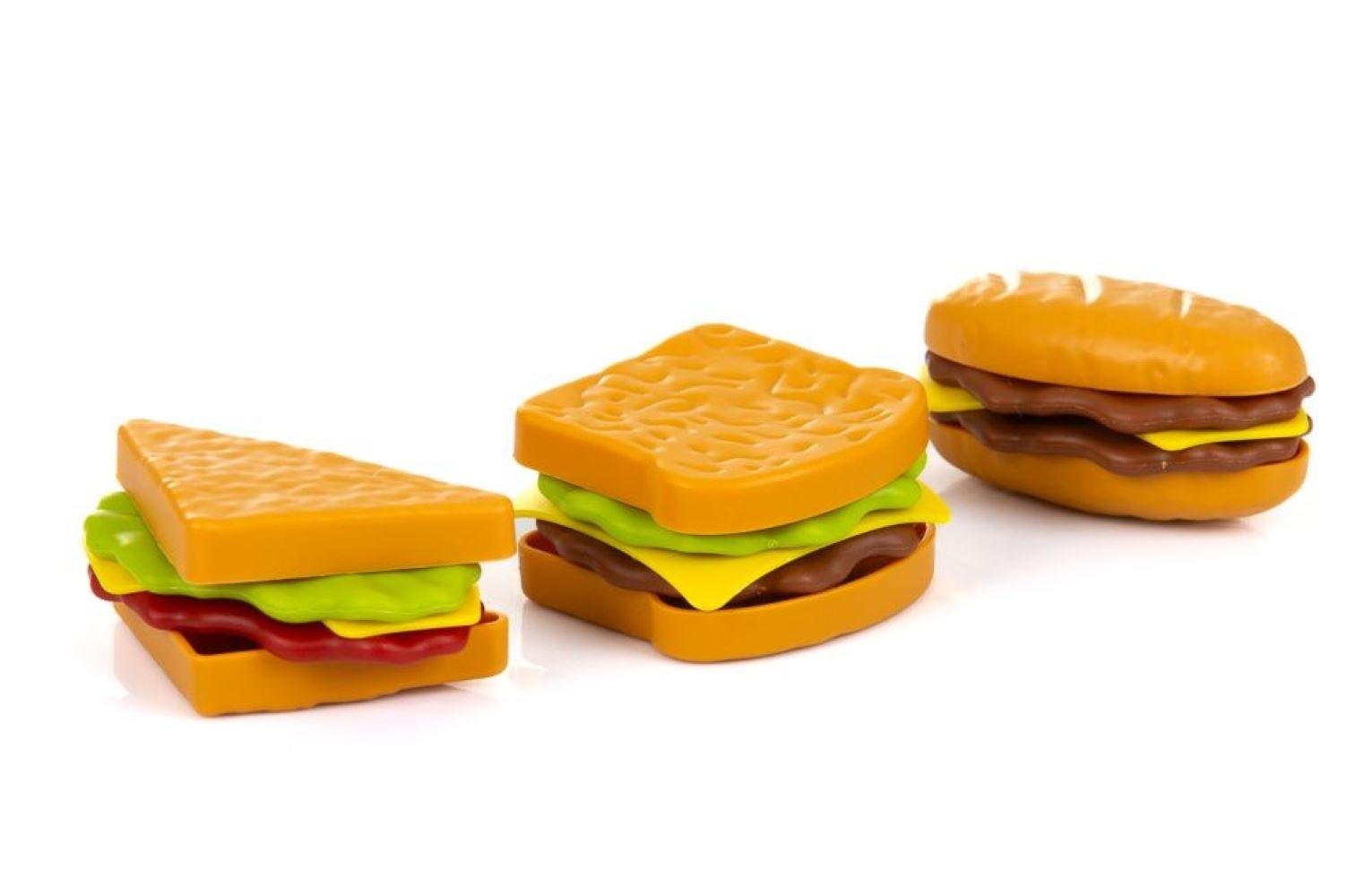 Drei bunte Plastik-Spielzeugsandwiches und ein Burger auf weißem Hintergrund.