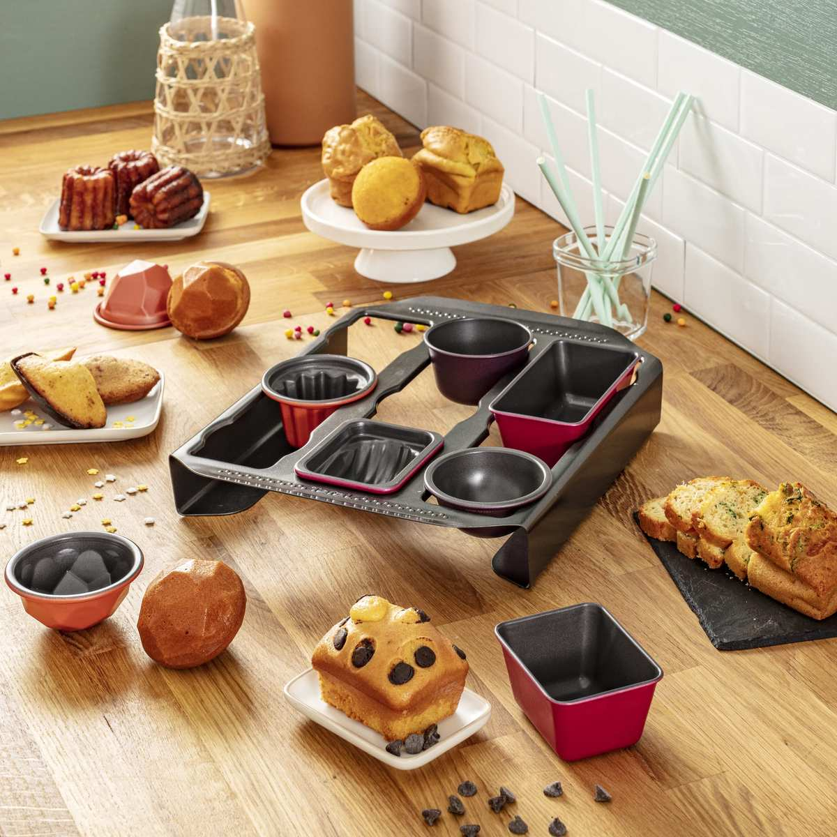 Backutensilien, verschiedene Backformen und frisch gebackene Kuchen auf einer Holztischplatte.