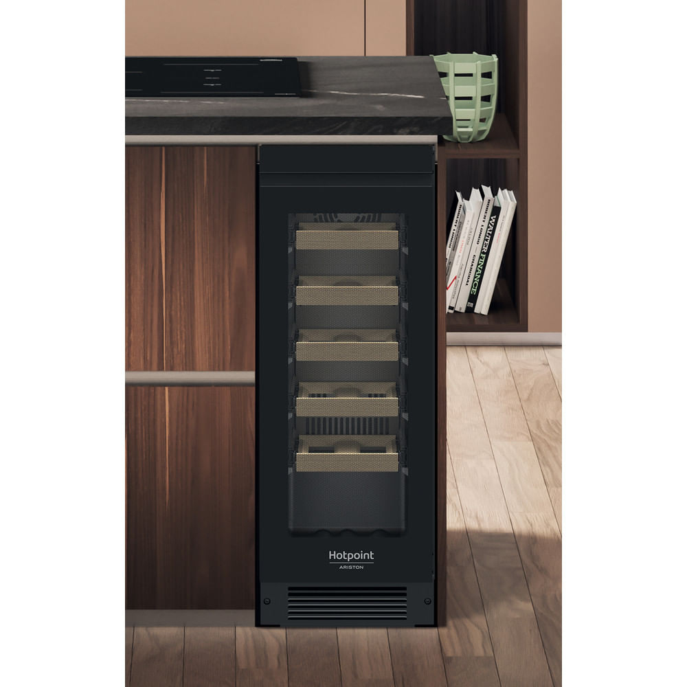 Una cantinetta per vini nera Hotpoint Ariston è integrata in mobili da cucina in legno con piano cottura.